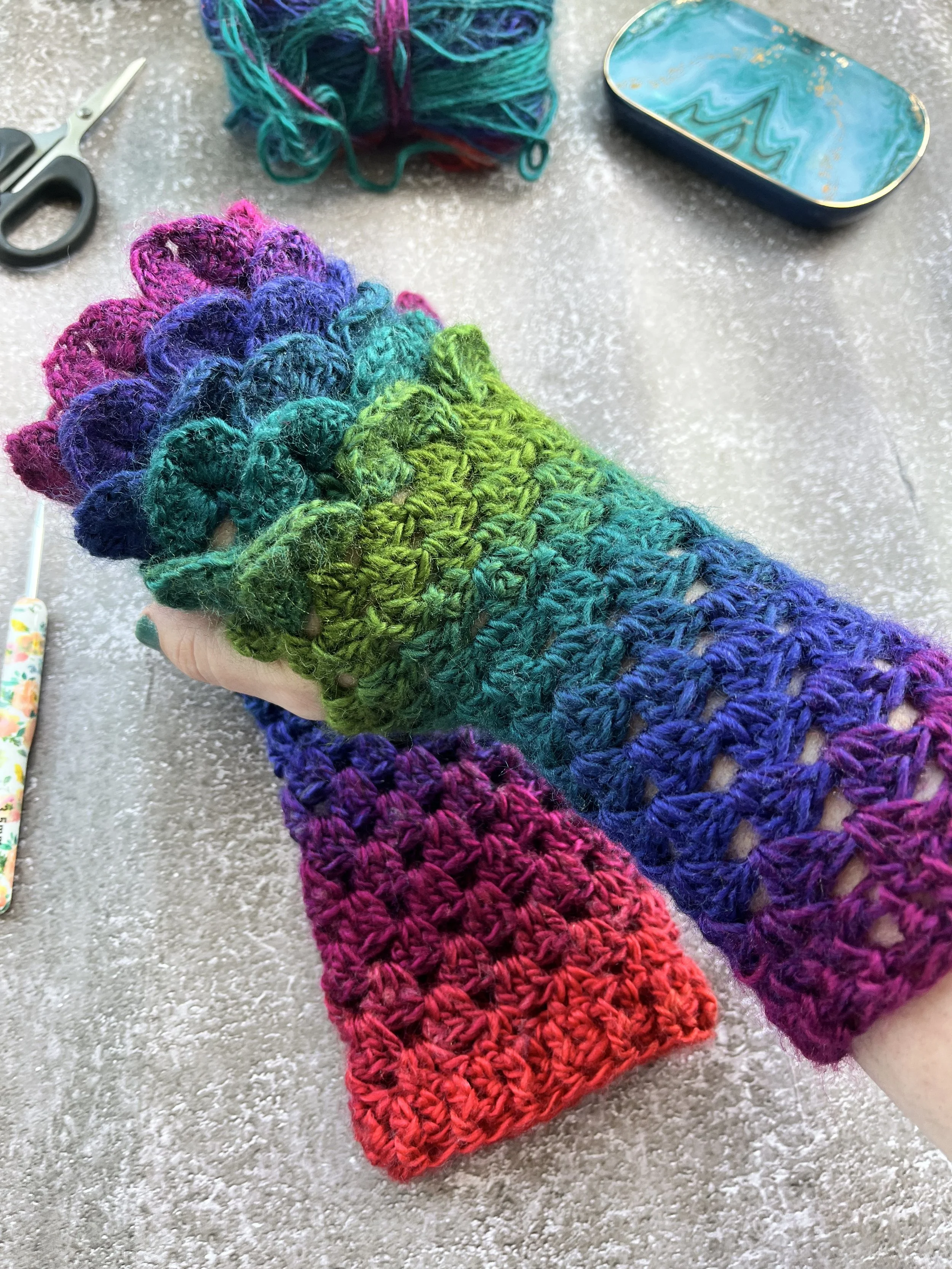 IMG_3980.jpeg A uniques pair of handmade crochet dragon scale type fingerless gloves in unique blend of purple, blue, teal, green and red. Close up look at the dragon scale effect