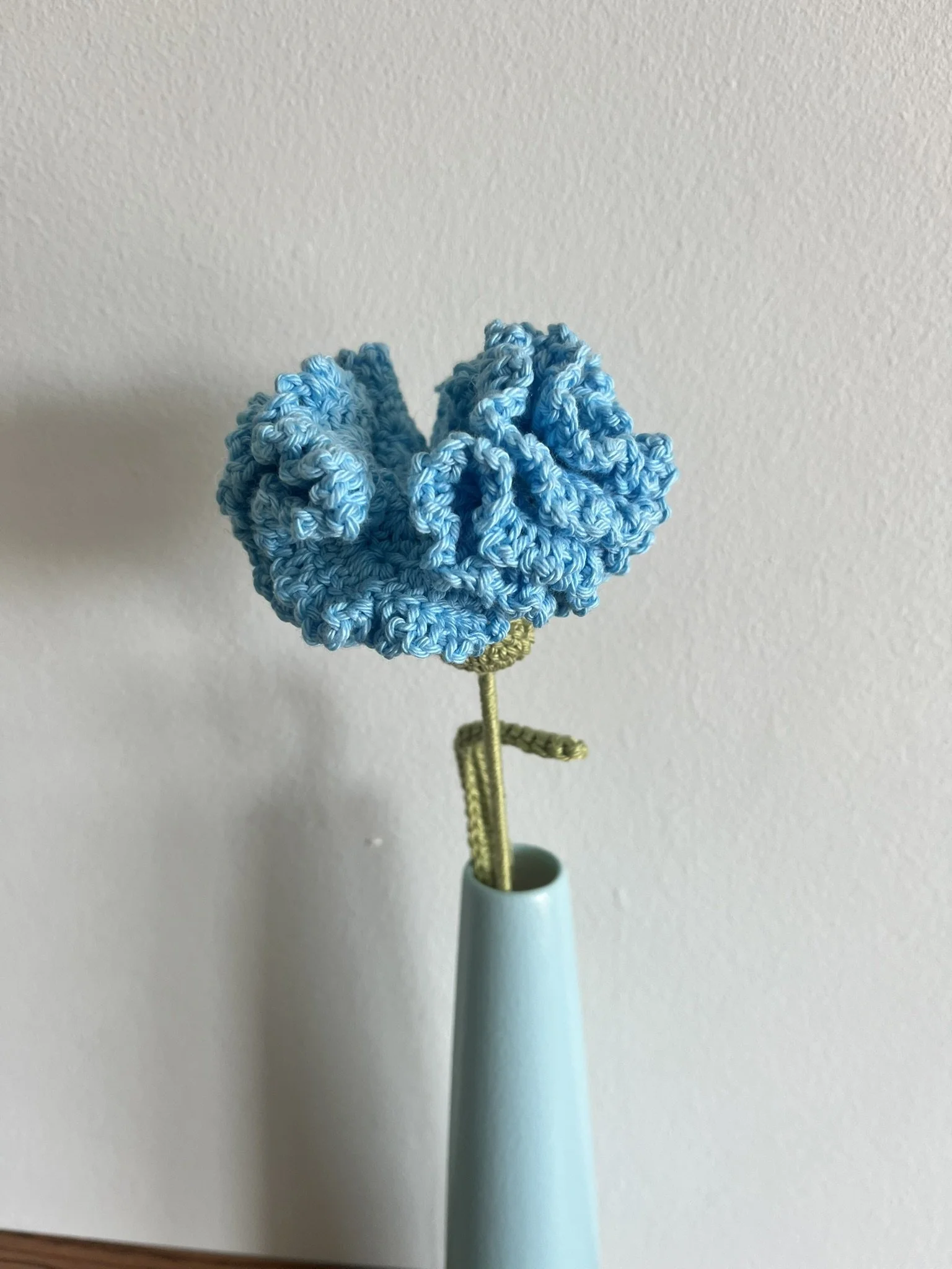 close-up of hand-crocheted carnation flower showing intricate crochet stitching and naturally frilly petals
