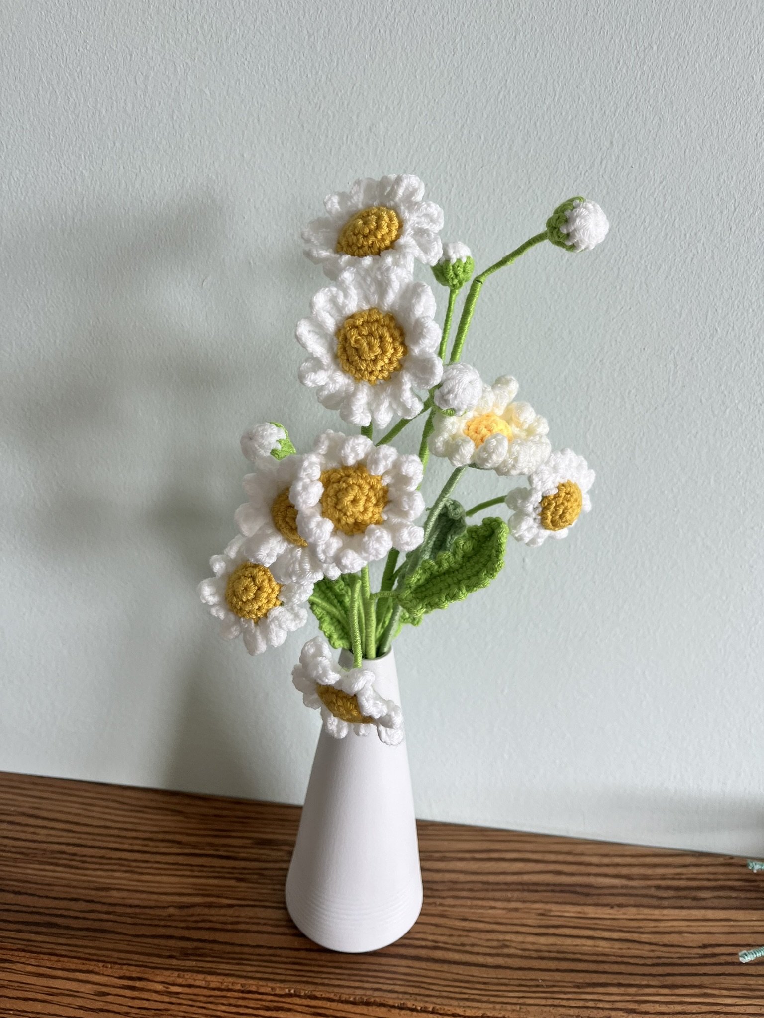 Close-up of hand-crocheted daisy flowers showing yellow centres and white petals with natural handmade variations