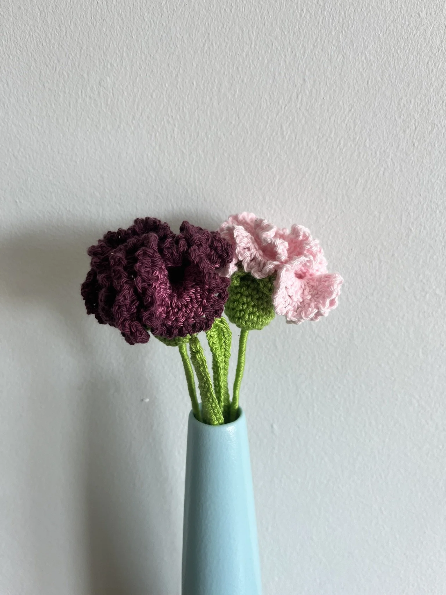 close-up of hand-crocheted carnation flower showing intricate crochet stitching and naturally frilly petals