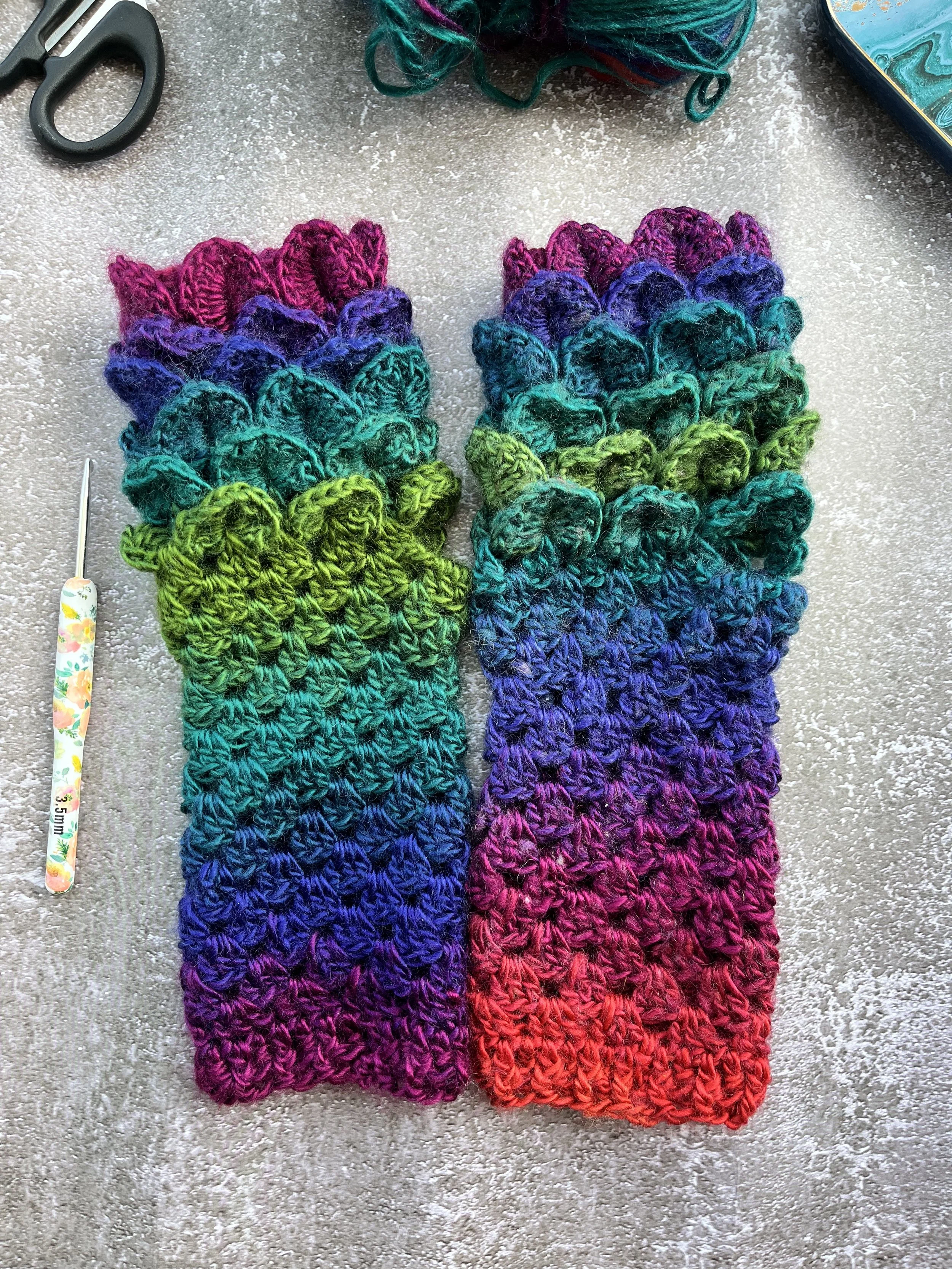 A uniques pair of handmade crochet dragon scale type fingerless gloves in unique blend of purple, blue, teal, green and red. One of a kind colour design