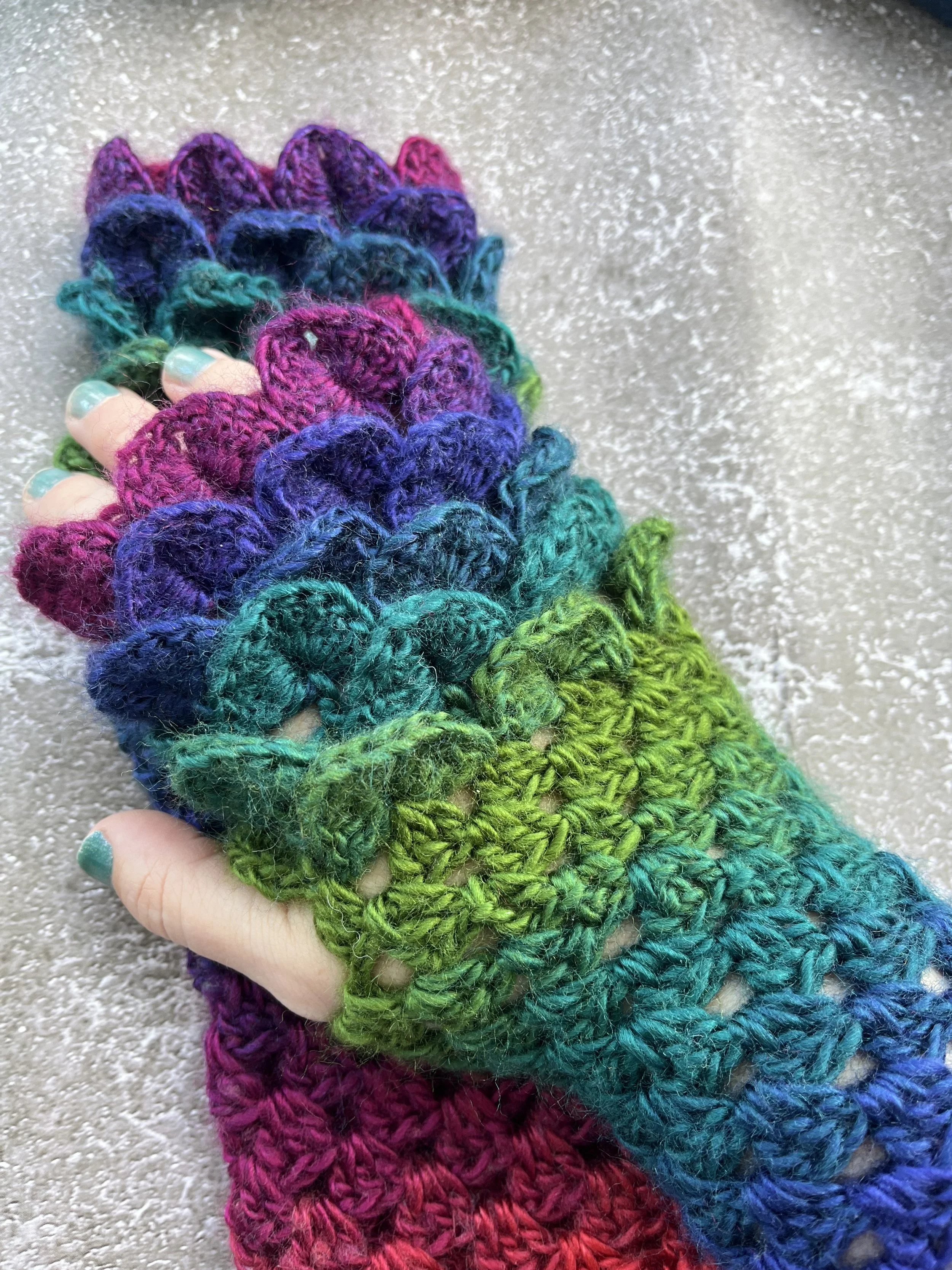 IMG_3981.jpeg A uniques pair of handmade crochet dragon scale type fingerless gloves in unique blend of purple, blue, teal, green and red. Close up look at the dragon scale effect