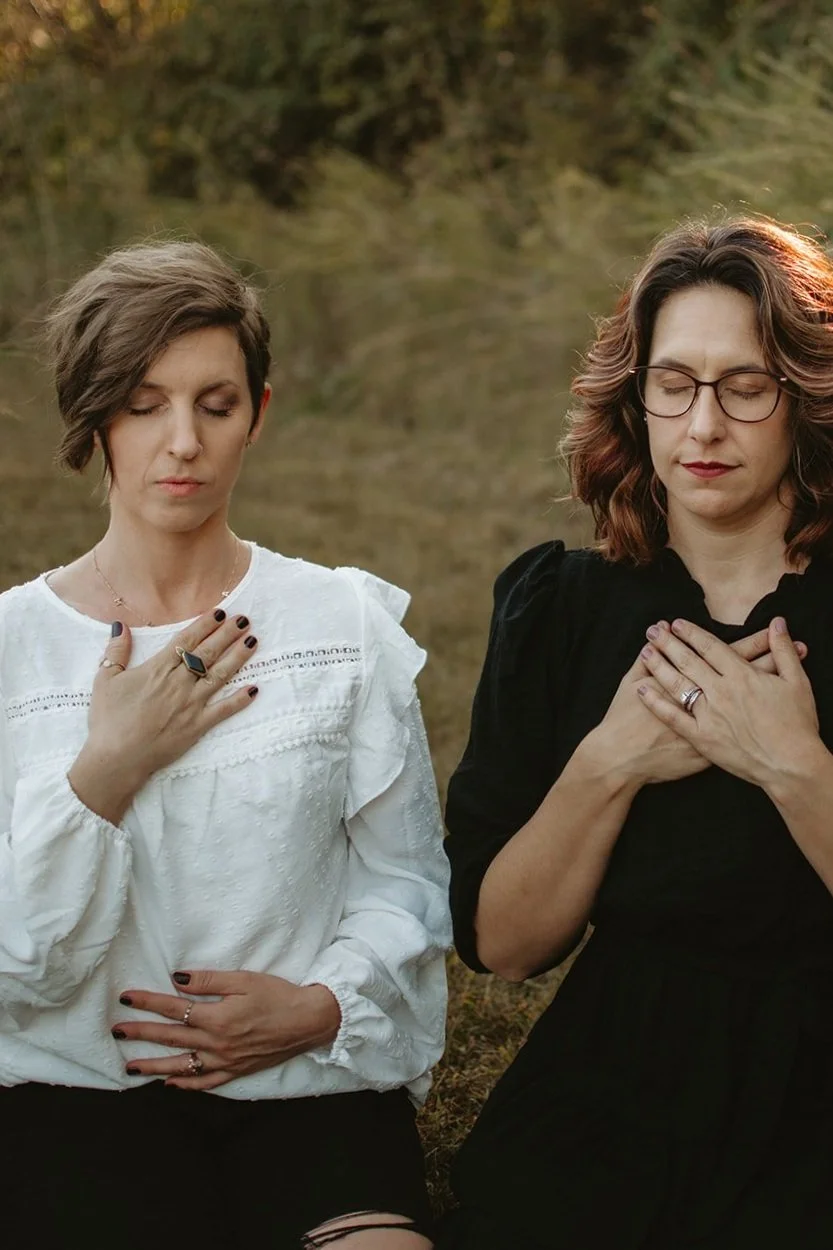 Two women sitting outdoors at sunset with their eyes closed practicing calm breathing, breathwork and meditation.