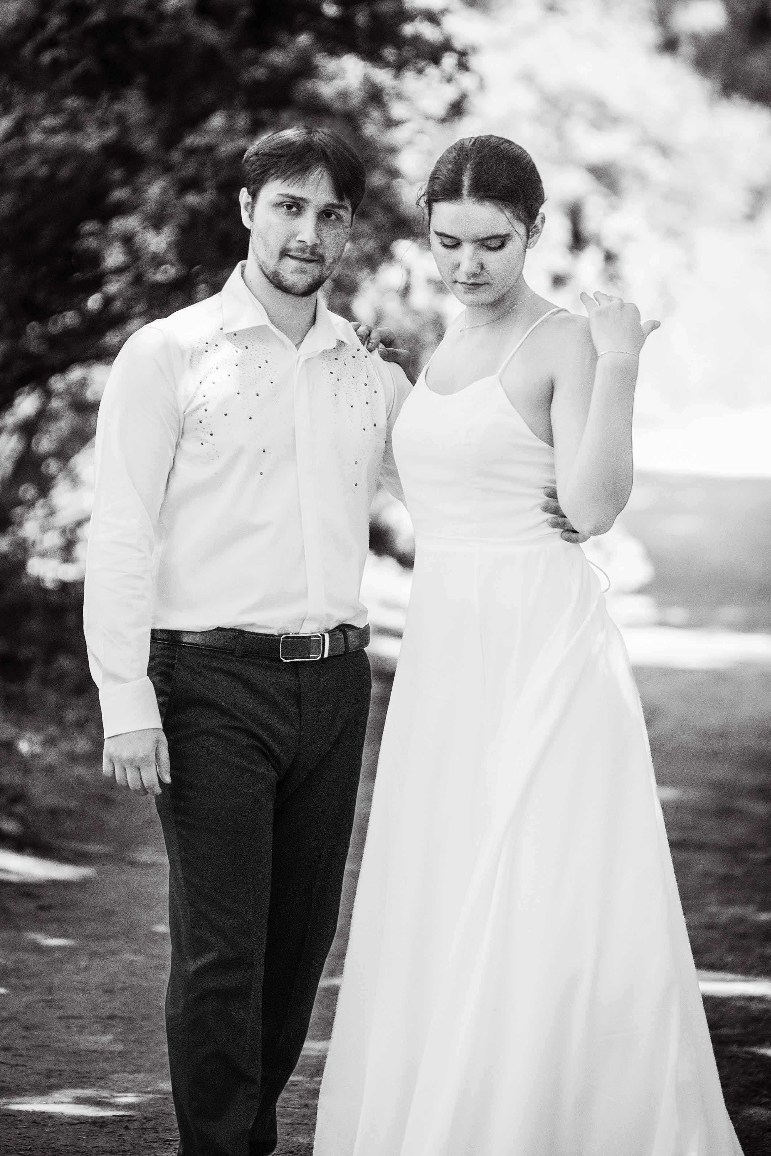 A sophisticated black-and-white portrait of a couple in a serene outdoor setting. Their graceful poses and natural expressions create a timeless and artistic image, perfect for capturing authentic moments.