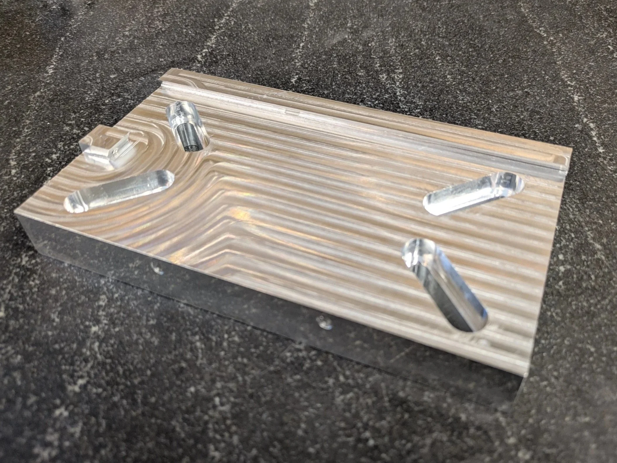 A glass sculpture resembling the outline of an airplane on a marble slab with a black granite surface.