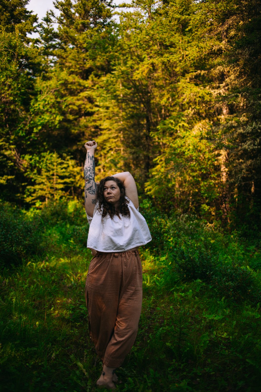 Jessica Huss in stretching position standing in a forest