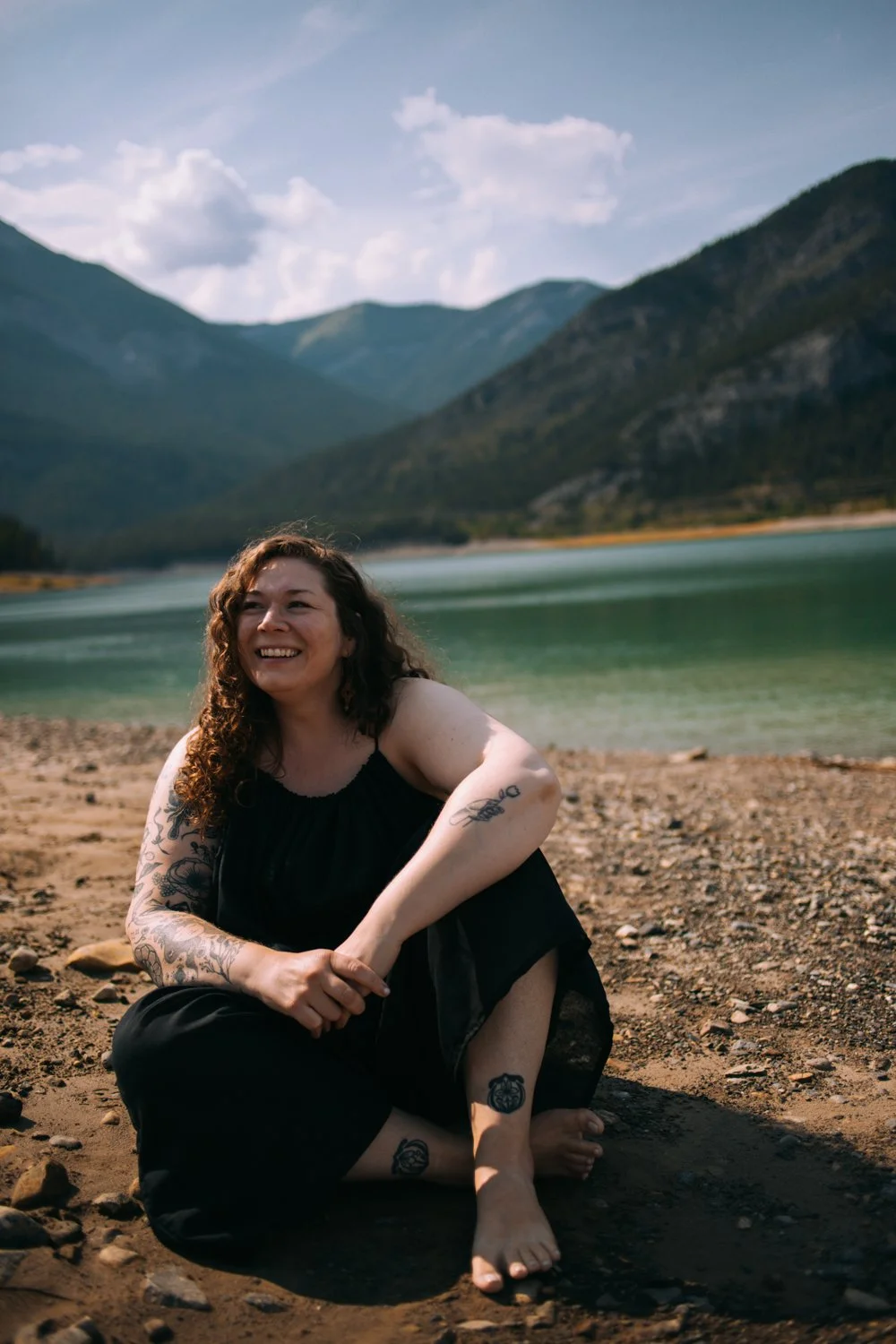 Jessica Huss smiling, seated outdoors with mountains and a lake in the background