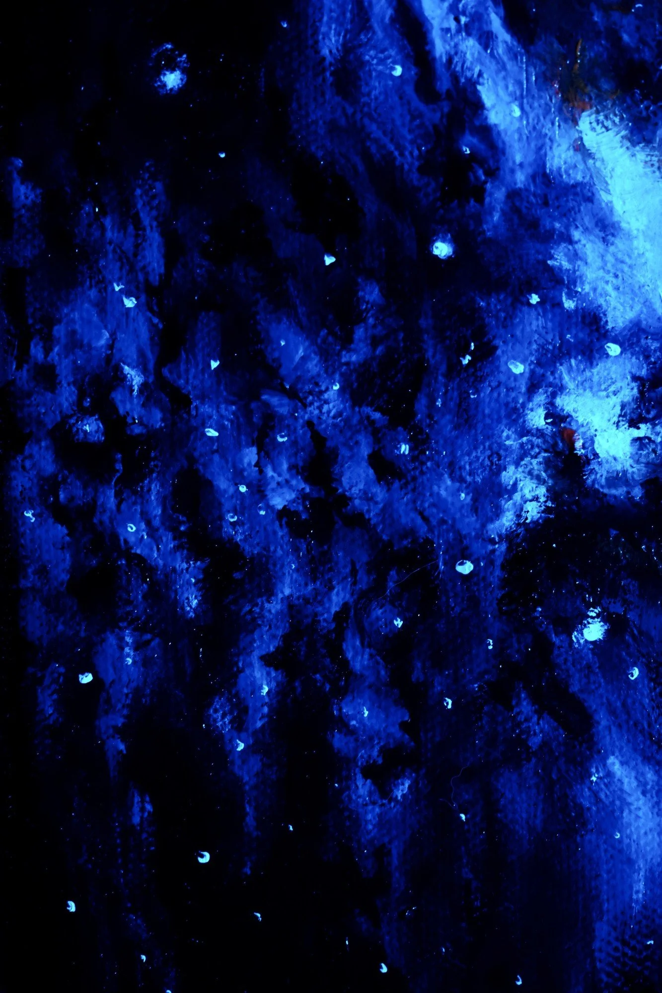 Glow-in-the-dark nebula painting photographed under blue light, luminous glow-in-the-dark stars