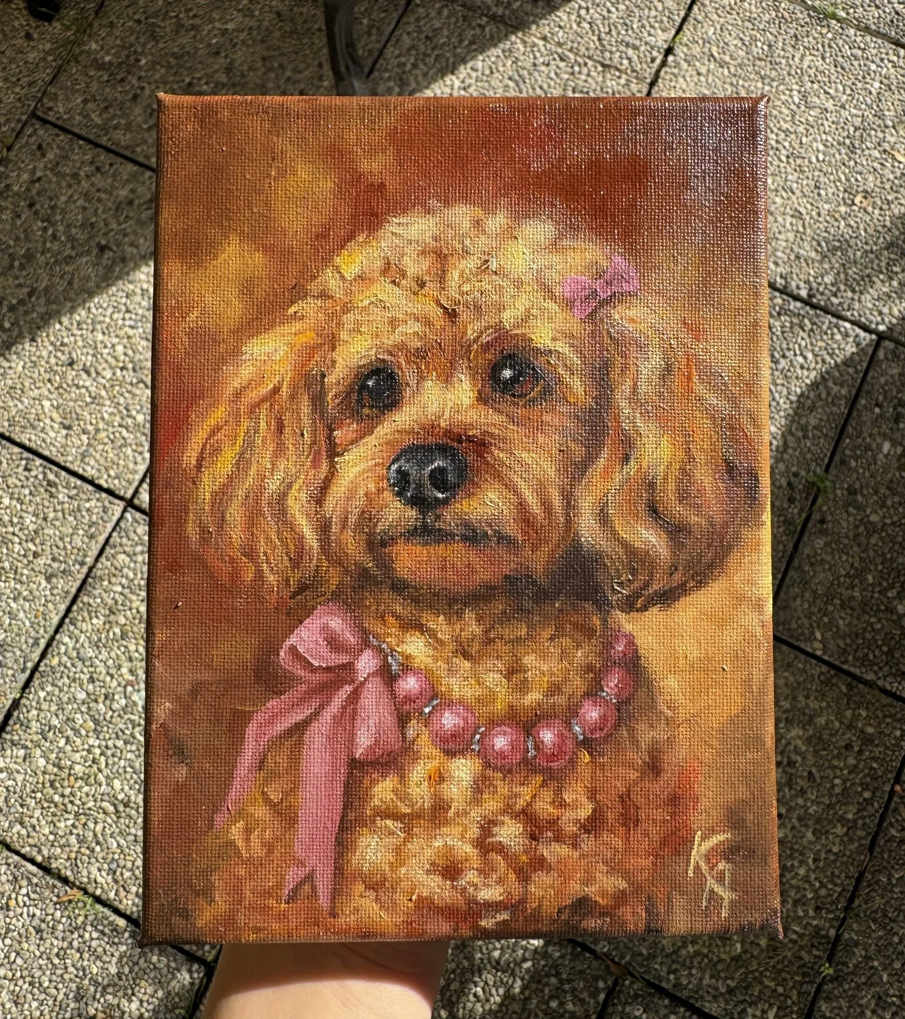 a finished oil painting of a curly-haired Poodle wearing a pink bow and pearl necklace