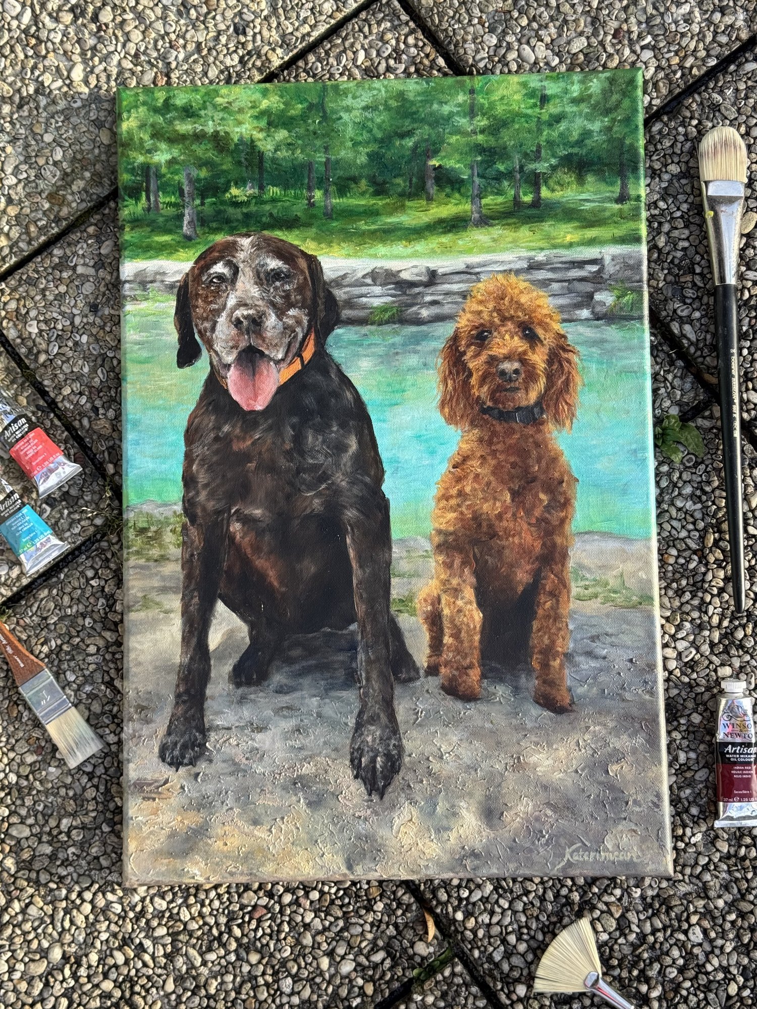 Oil painting of a chocolate Labrador and a red Poodle sitting together by a turquoise lake, forest background