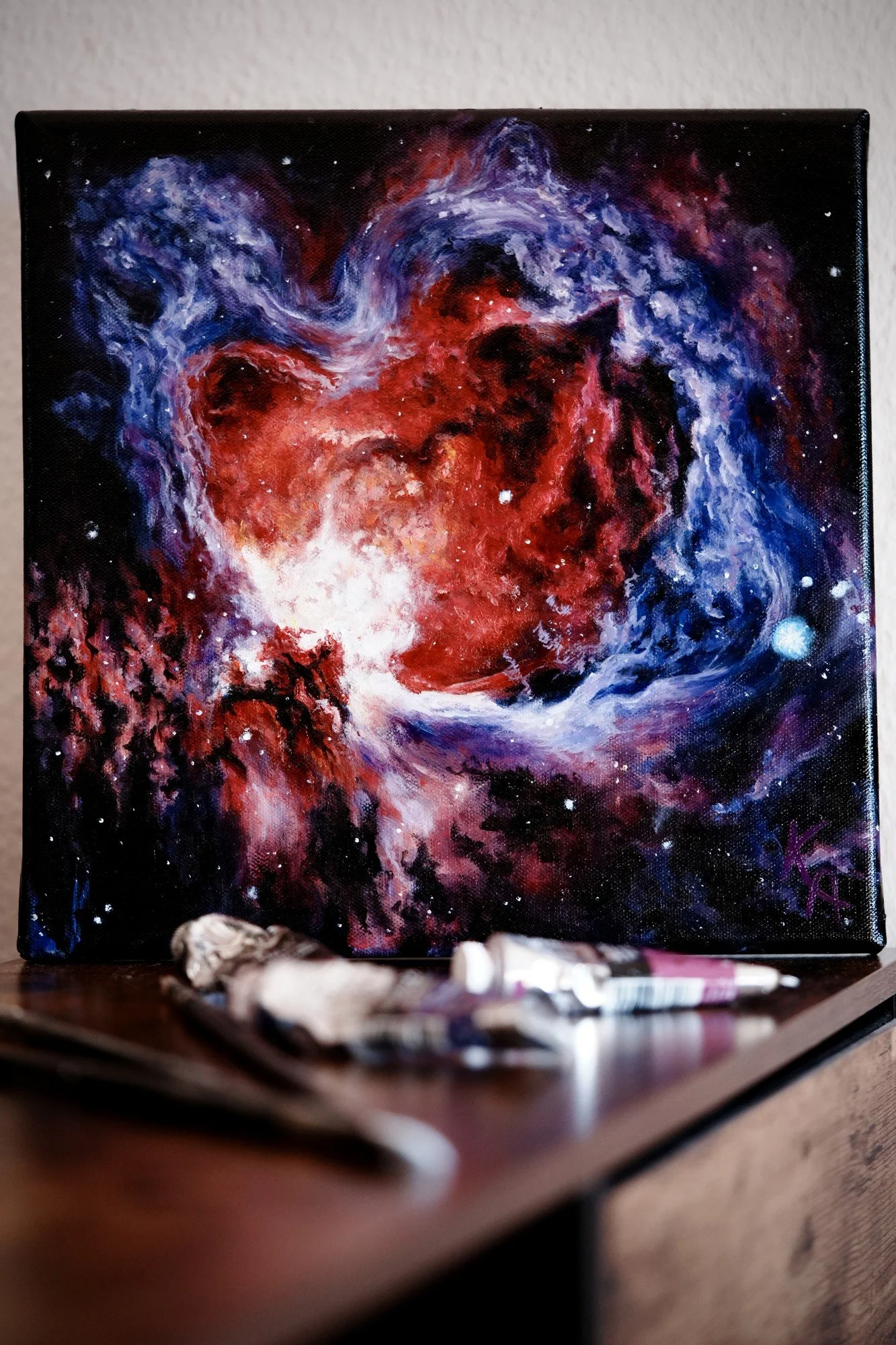 Glow-in-the-dark nebula oil painting on canvas in daylight showing red and blue nebula clouds