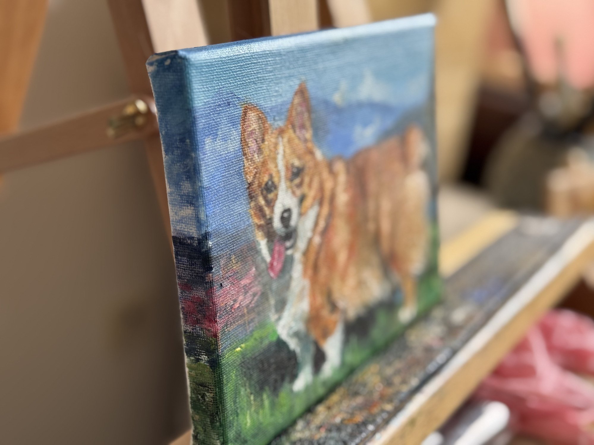 Side view of a Corgi oil painting showing canvas edge and paint texture on a wooden easel