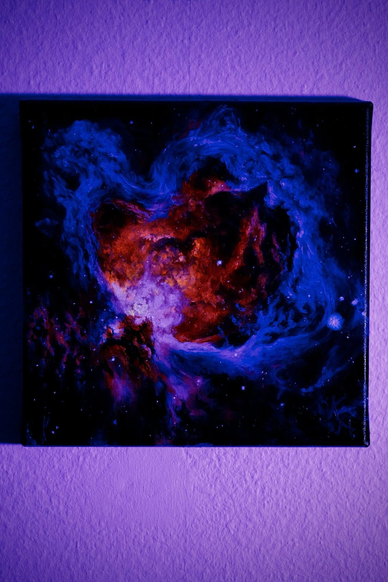 Glow-in-the-dark nebula painting photographed under purple UV light, showing luminous glowing stars