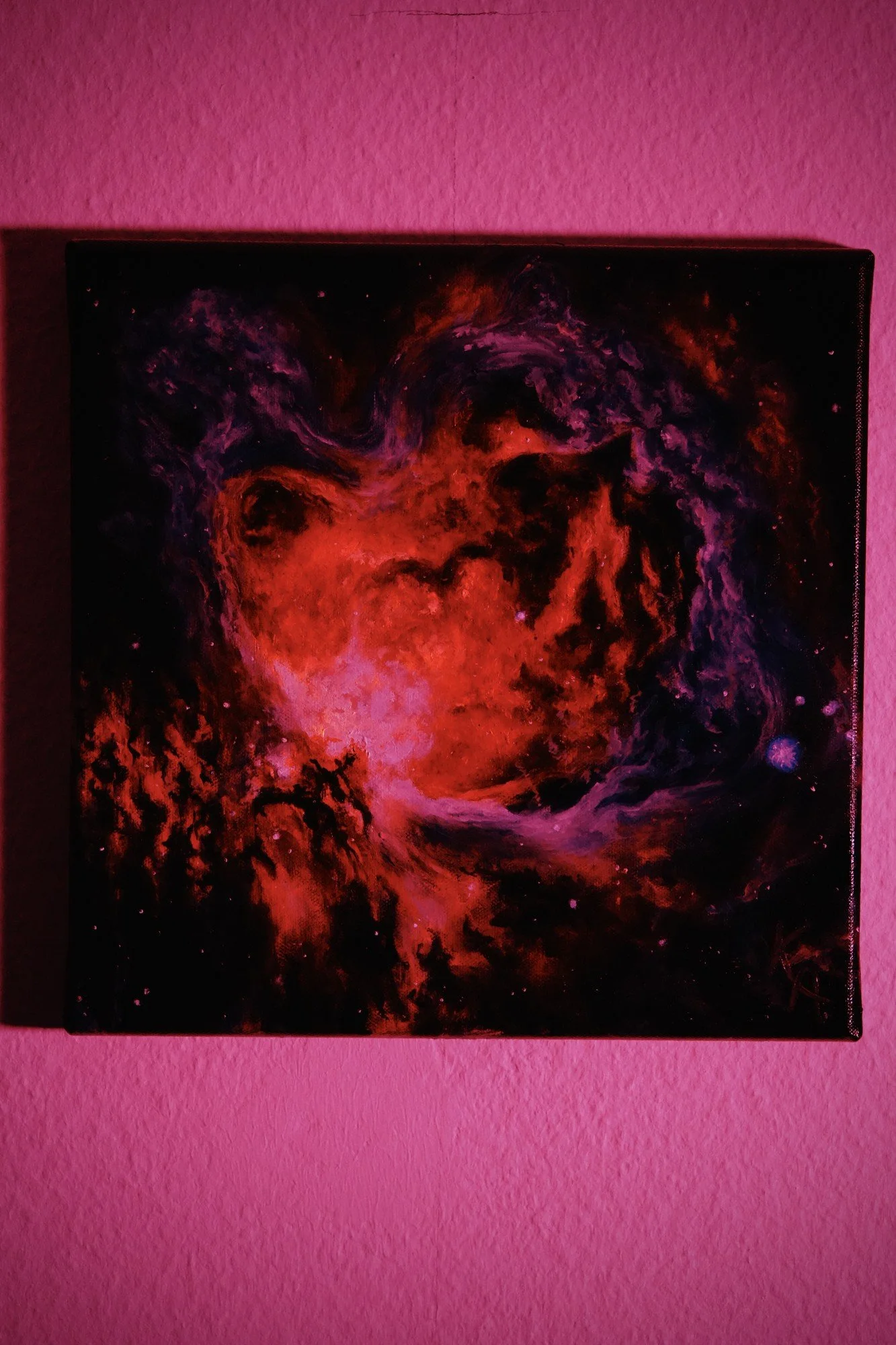Glow-in-the-dark nebula painting photographed under red light, phosphorescent glow effect