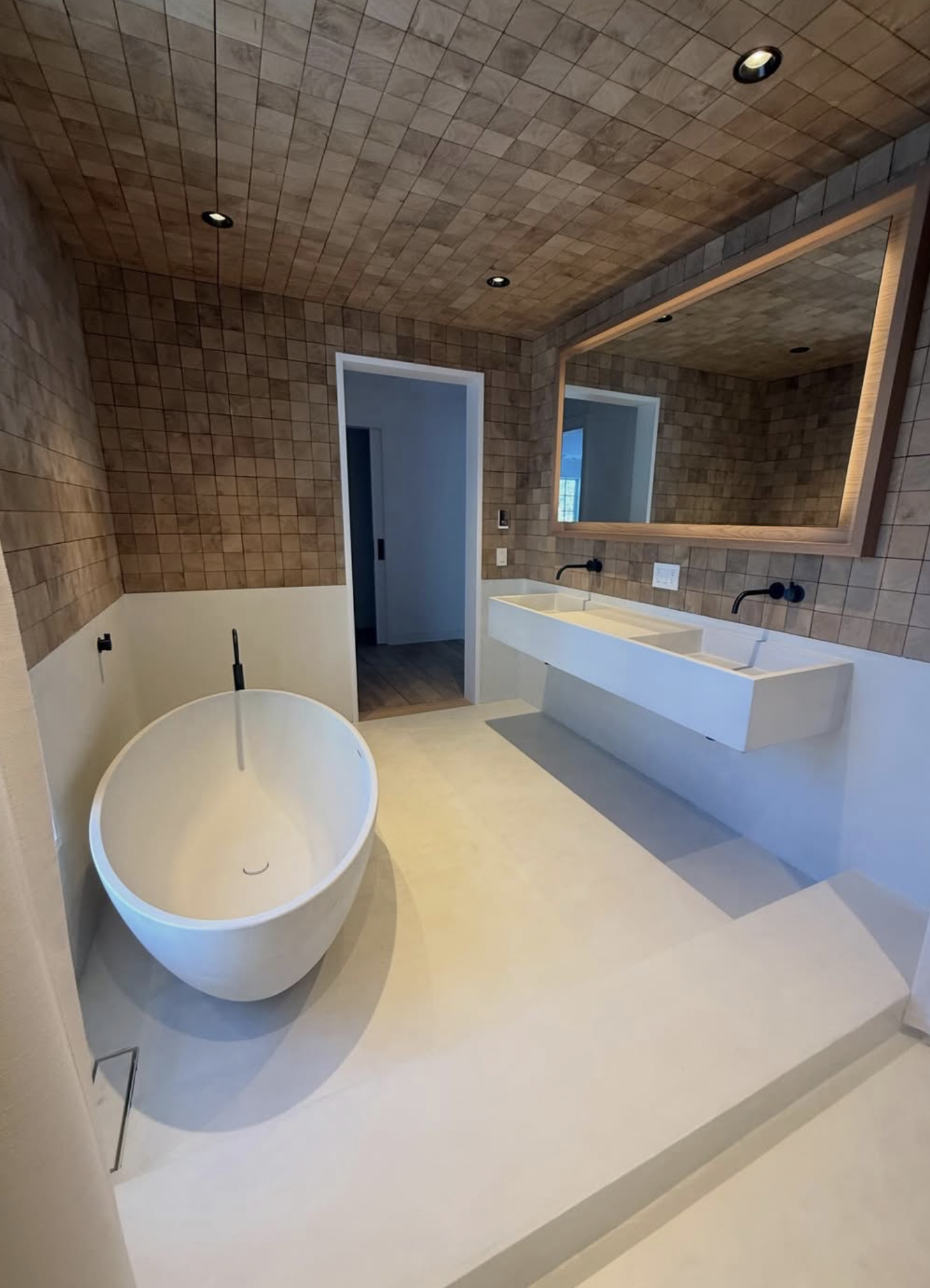 Modern bathroom renovation with micro-cement finishes and wood tile walls and ceiling. 