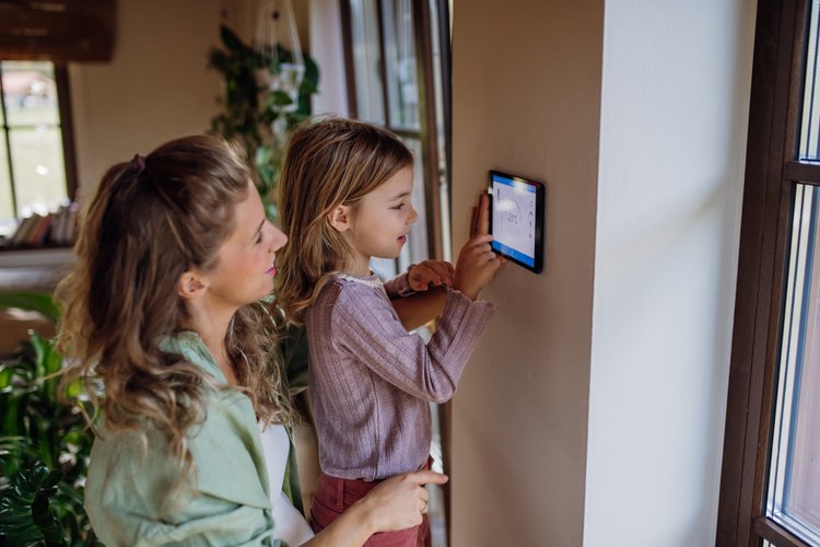 A young girl assisting her mother in adjusting the thermostat, highlighting family comfort and energy efficiency at home