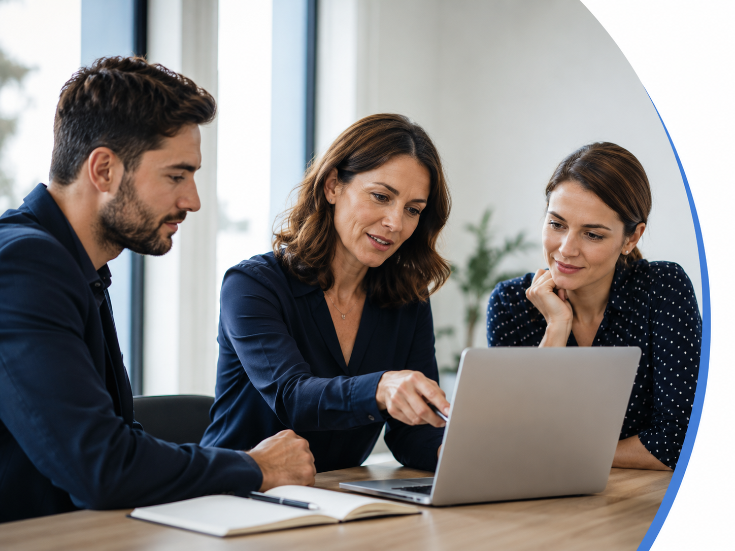 Three colleagues, two women and one man, collaborating around a laptop in a bright office space.