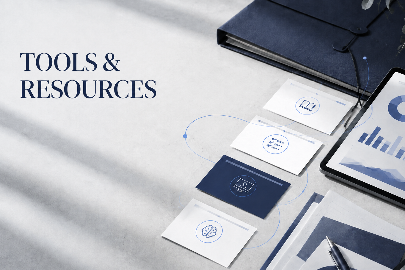Top view of a workspace with a tablet displaying charts, a closed blue notebook, printed notes with icons, a pen, and documents on a light surface. Text reads 'Tools & Resources'.