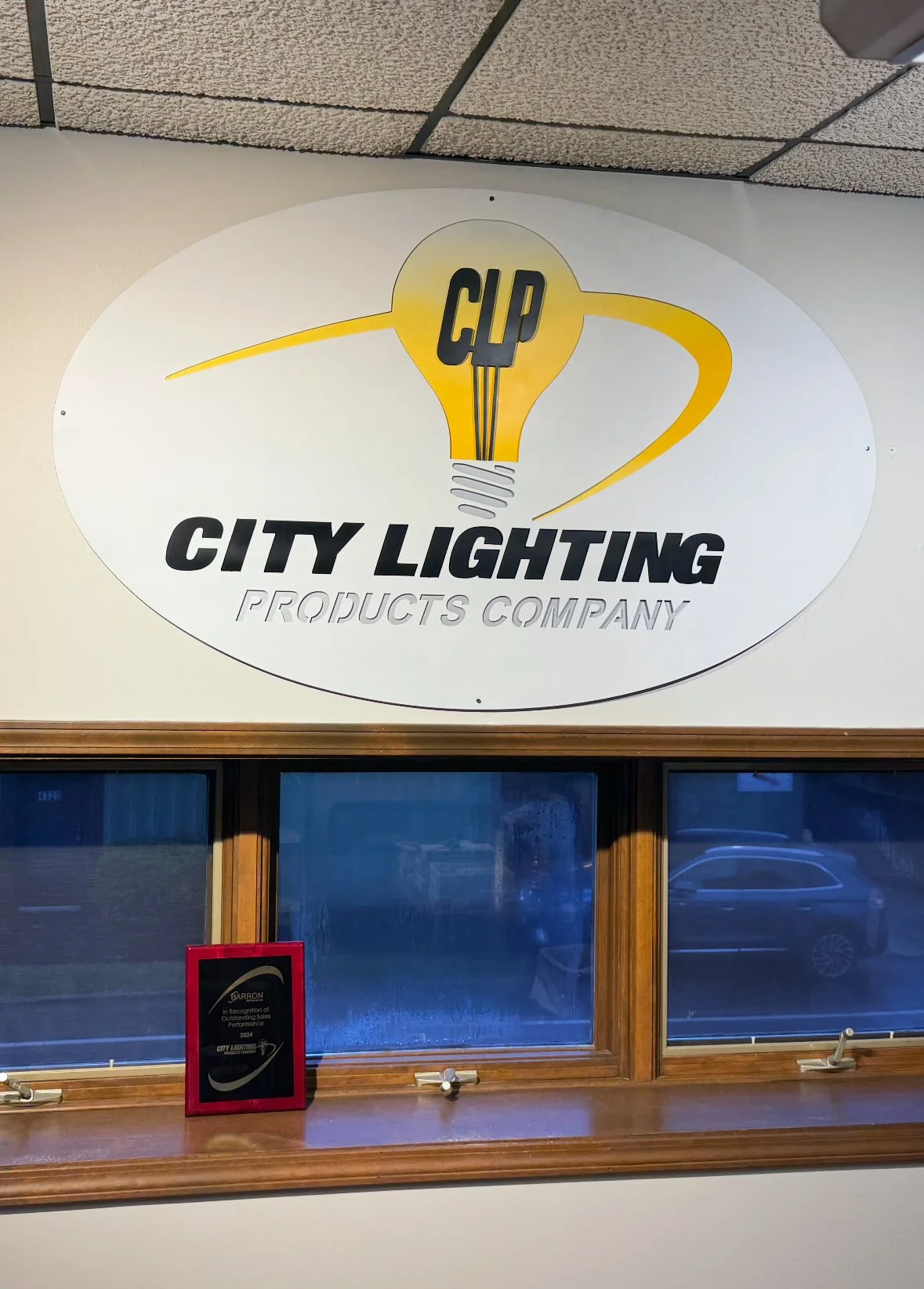 Sign for City Lighting Products Company with a yellow light bulb graphic and a window below it.