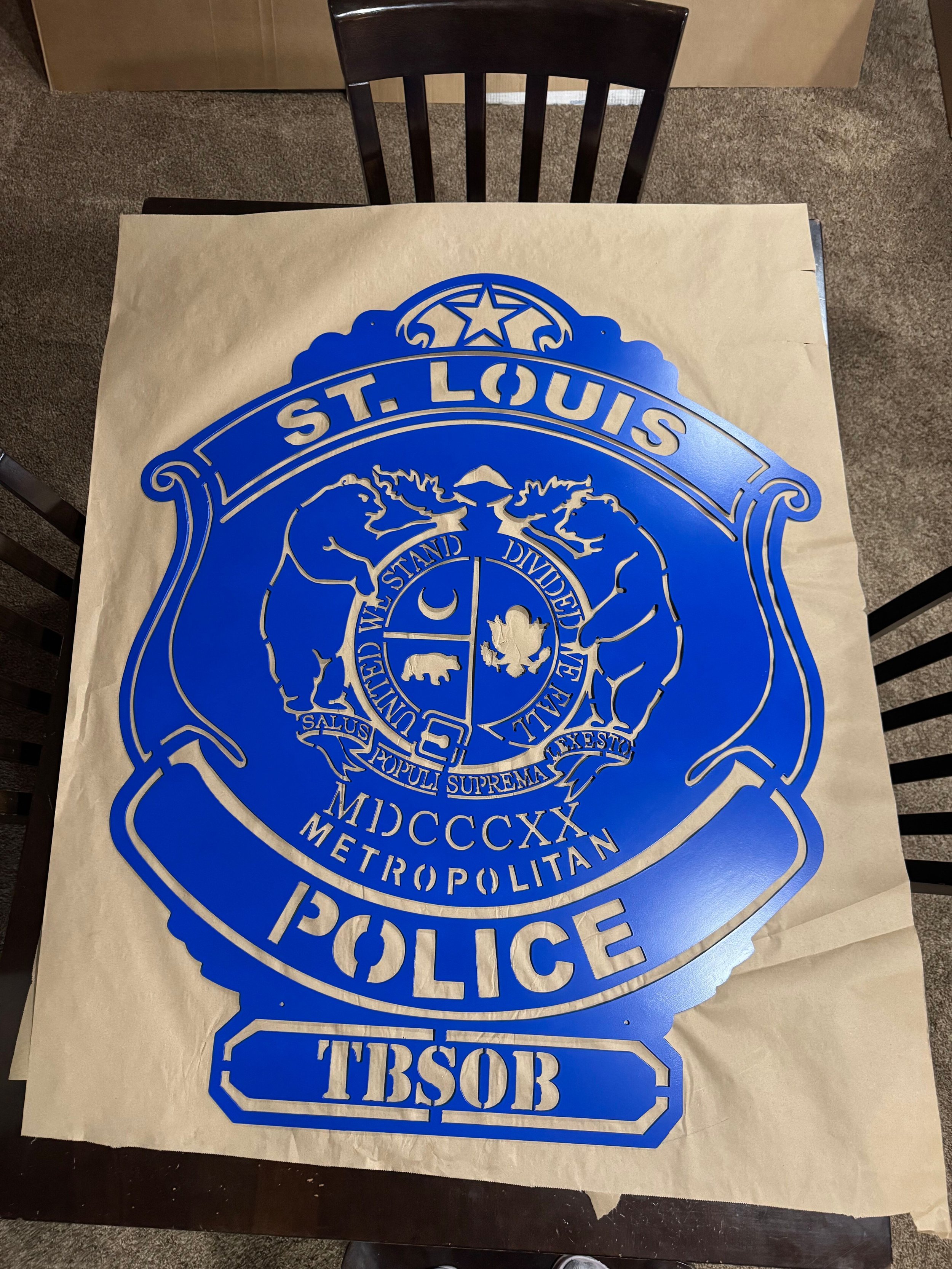 Blue sticker of the St. Louis Metropolitan Police badge on a piece of paper on a table.