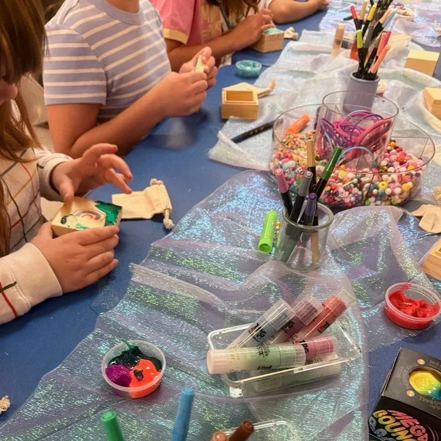 Paint pens, markers, and beads set out for a birthday party craft project