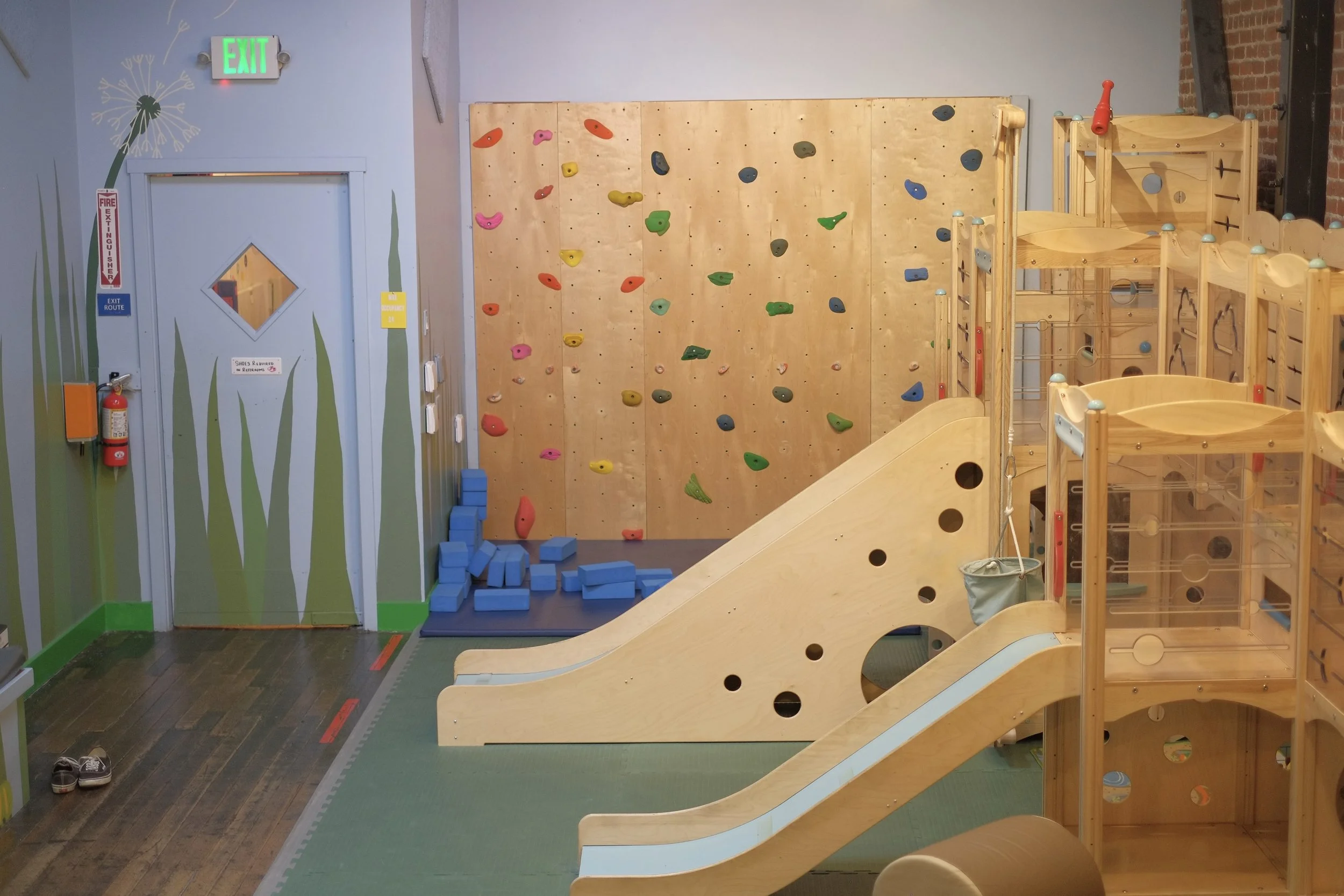 The Play Room at Art Play Café in Petaluma, featuring a climbing wall, wooden play structure, and slide