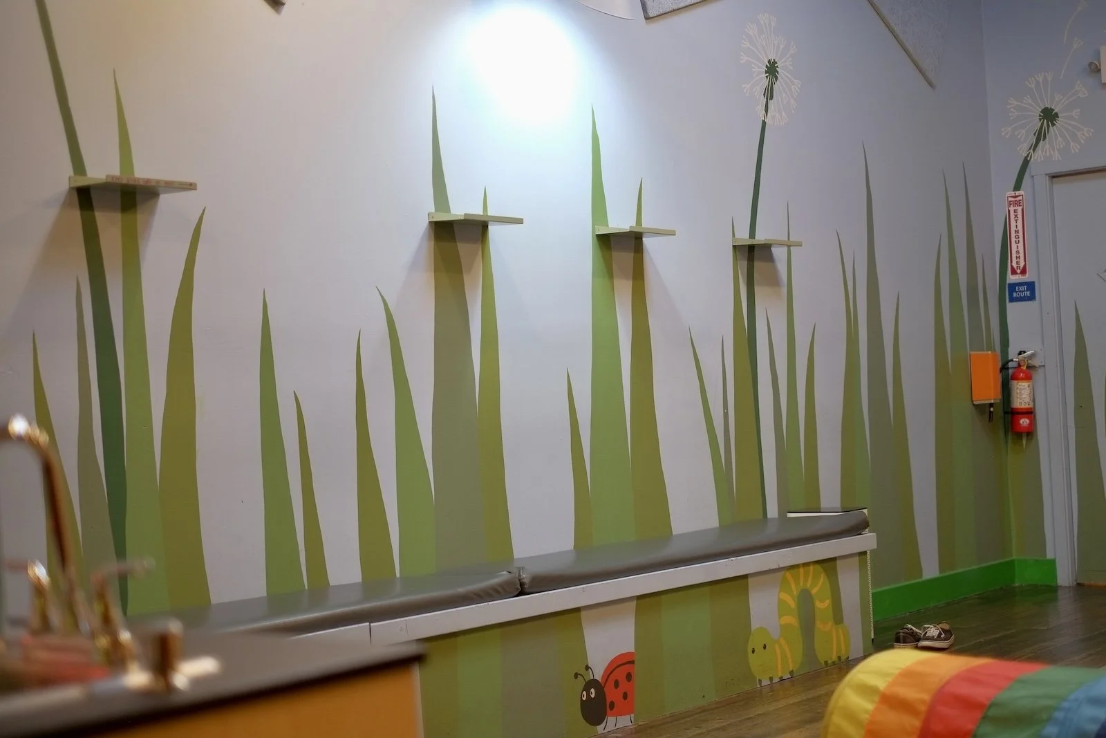 Grass mural with sitting bench for grown ups and shelves for coffee drinks in play room