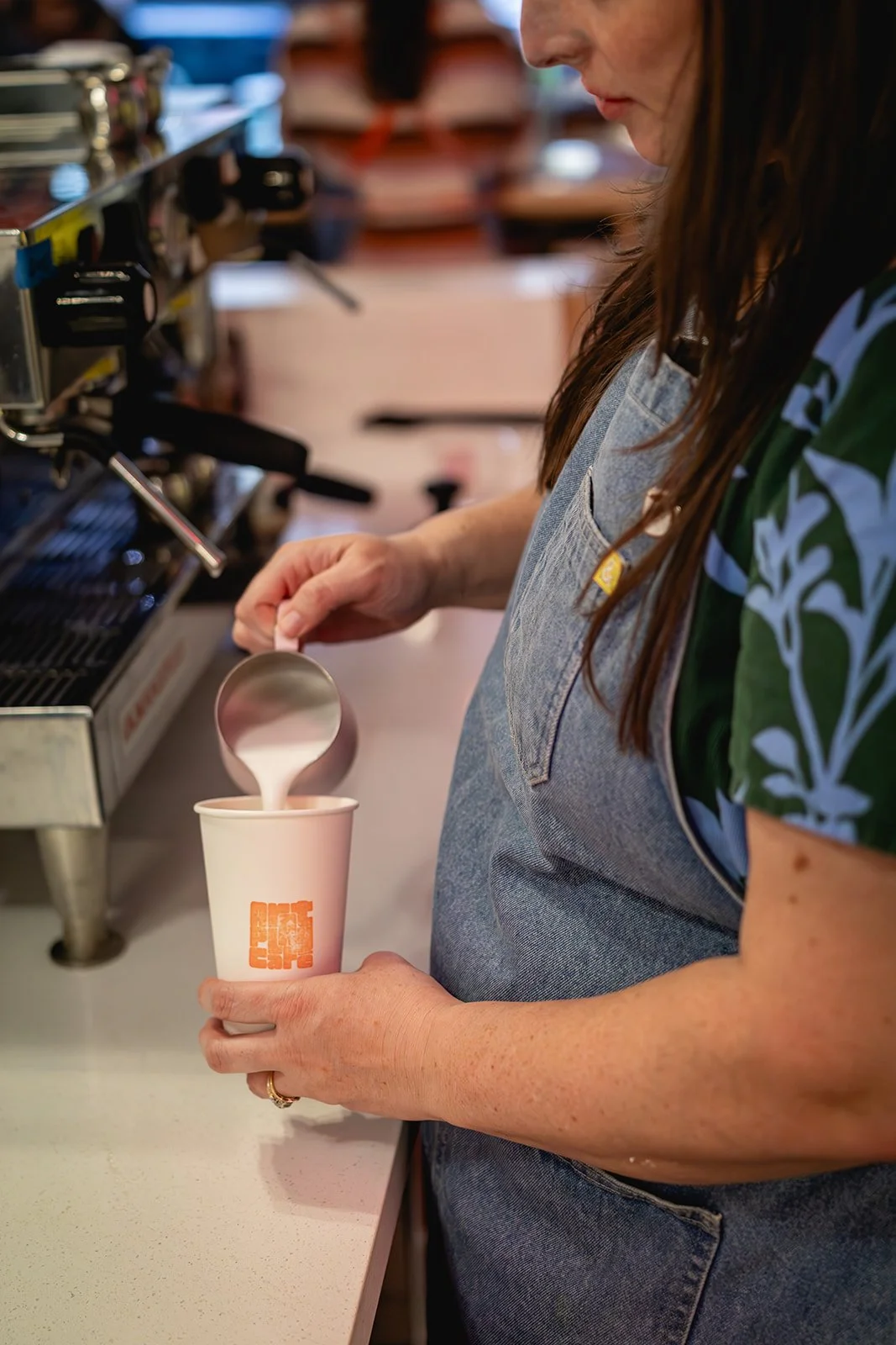 Barista pouring steamed milk into a hot drink at Art Play Café