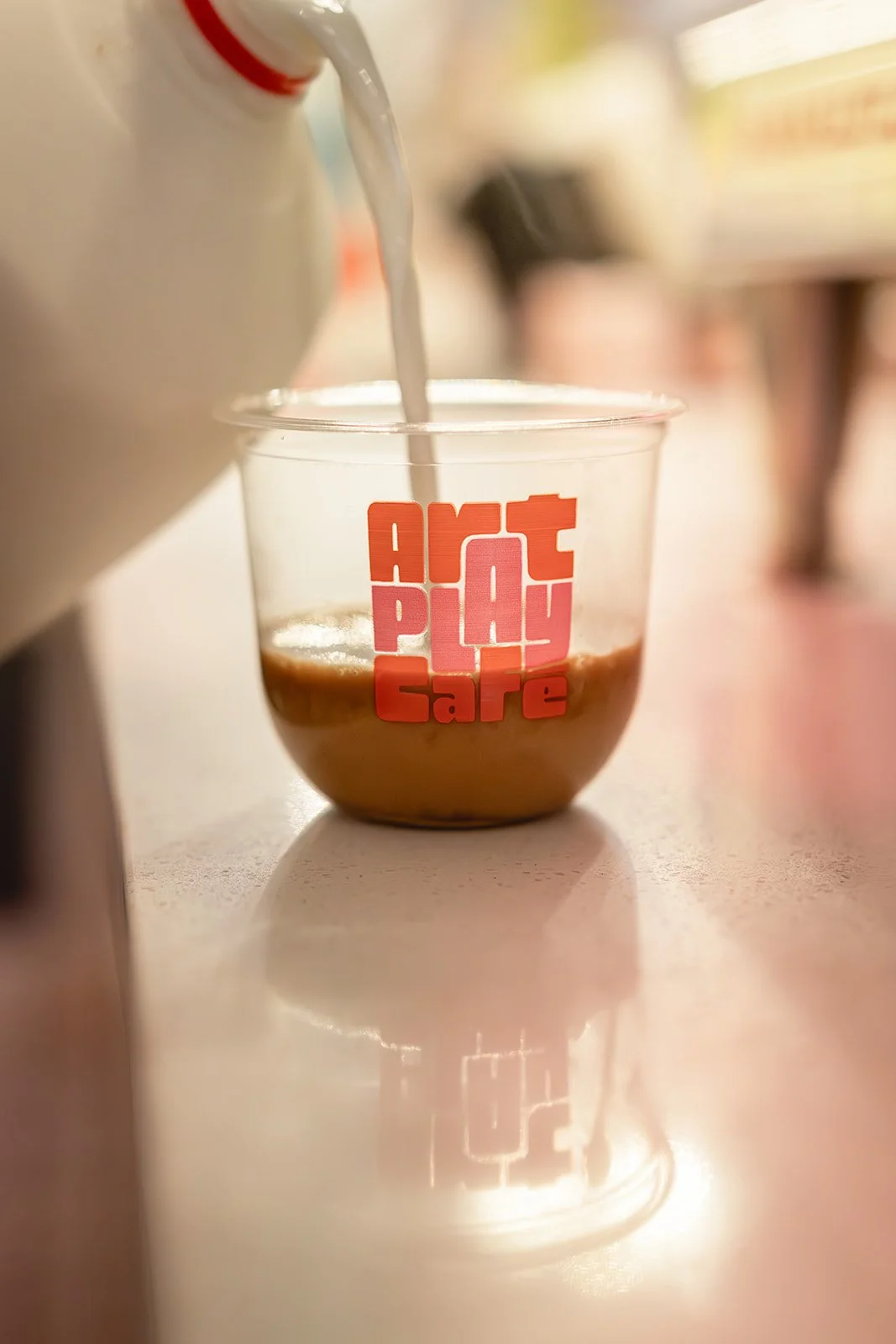 Milk being poured into espresso in an Art Play Café branded cup