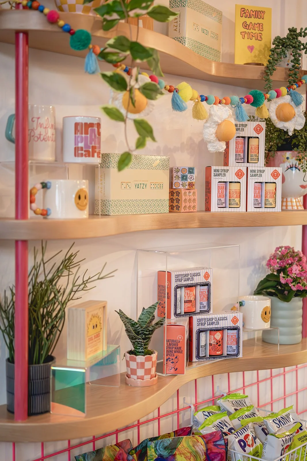 Art Play Café branded mugs and syrup samplers displayed on a retail shelf