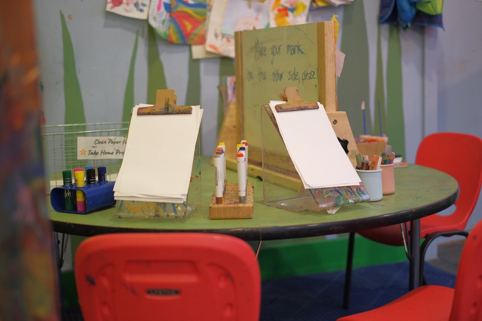 Art easel station with paper and paint set up for open-ended creativity in the play room