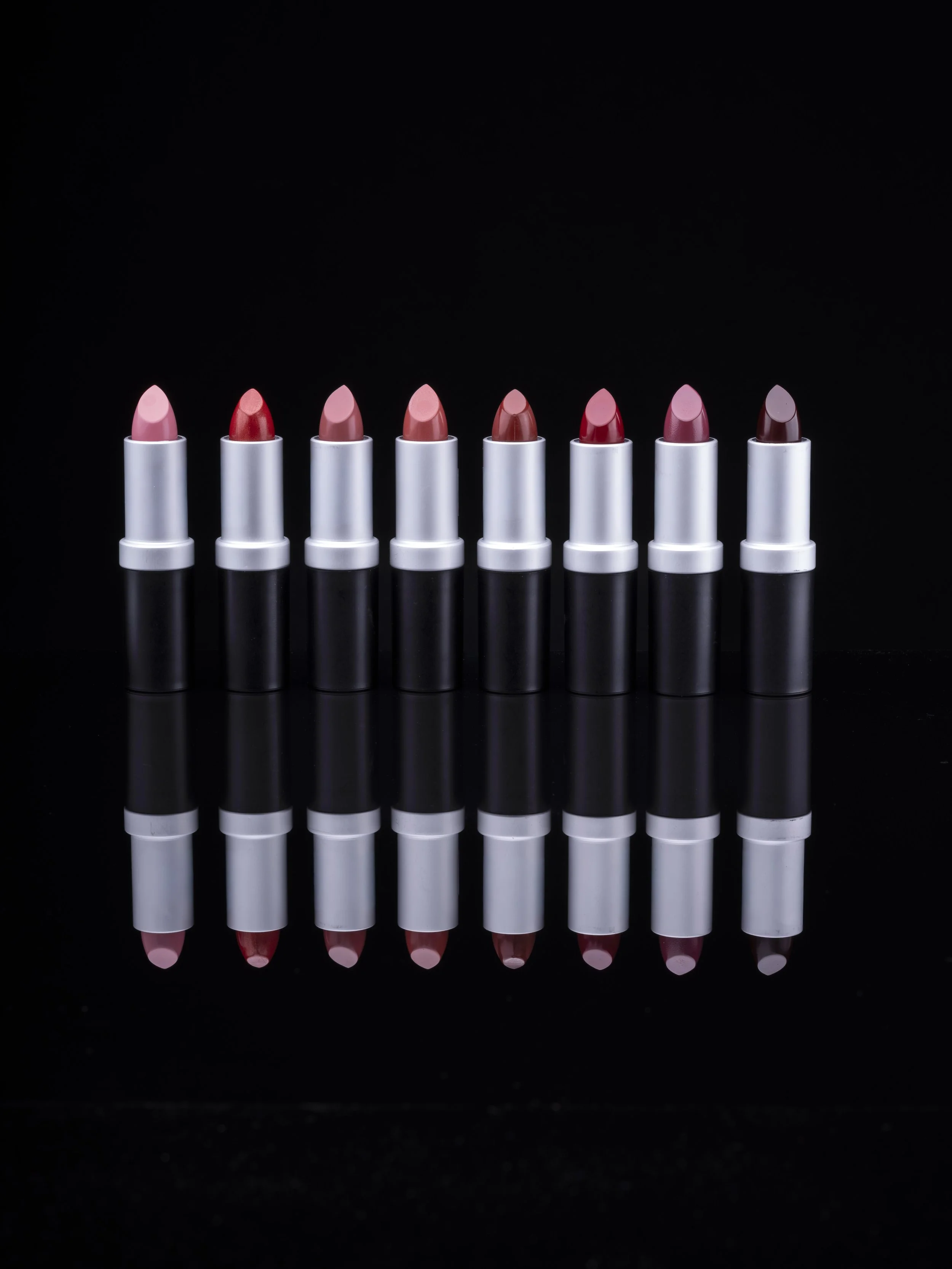 Lipstick products on a black reflective surface.