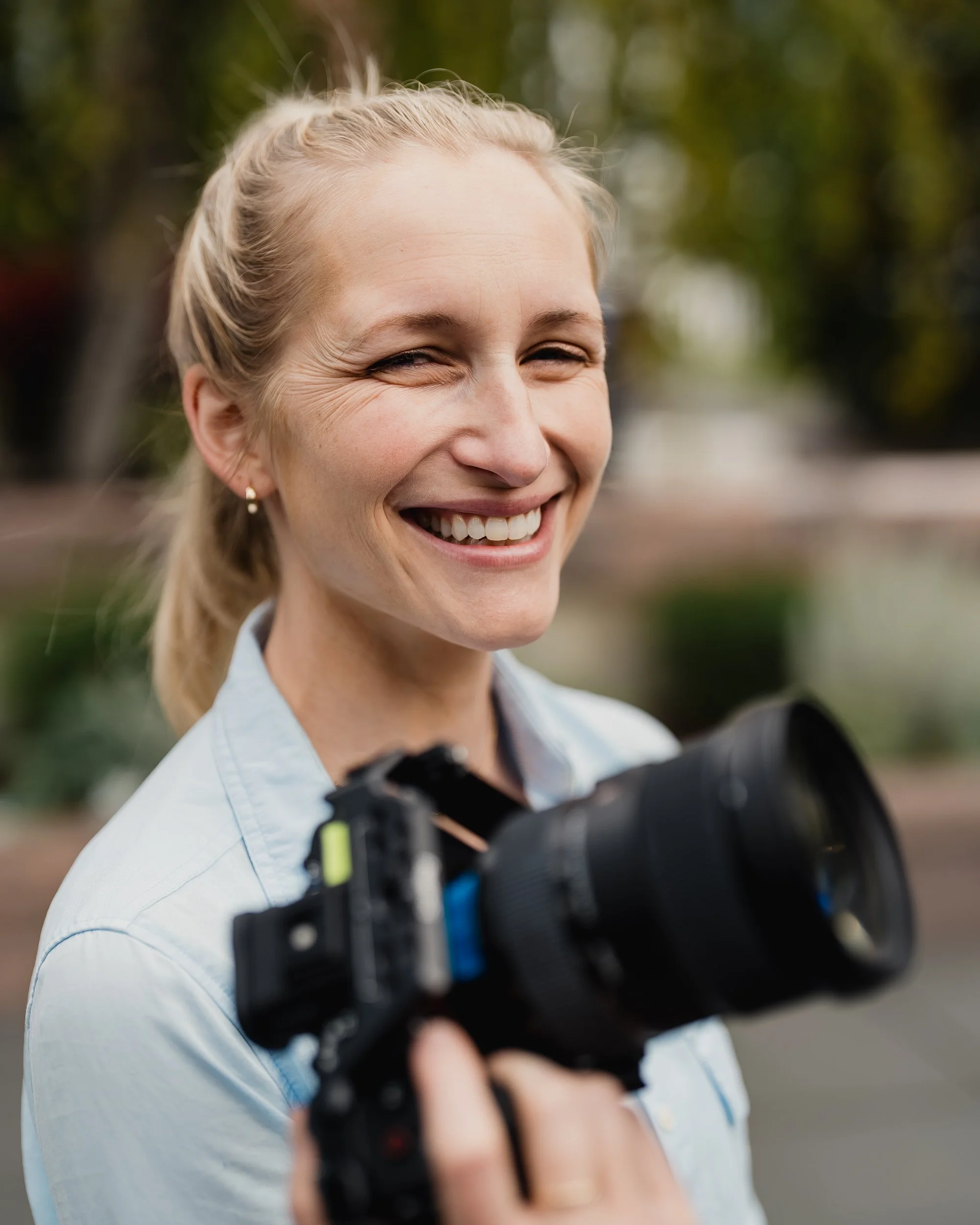 Photographer Kat Britten smiling outdoors with her camera