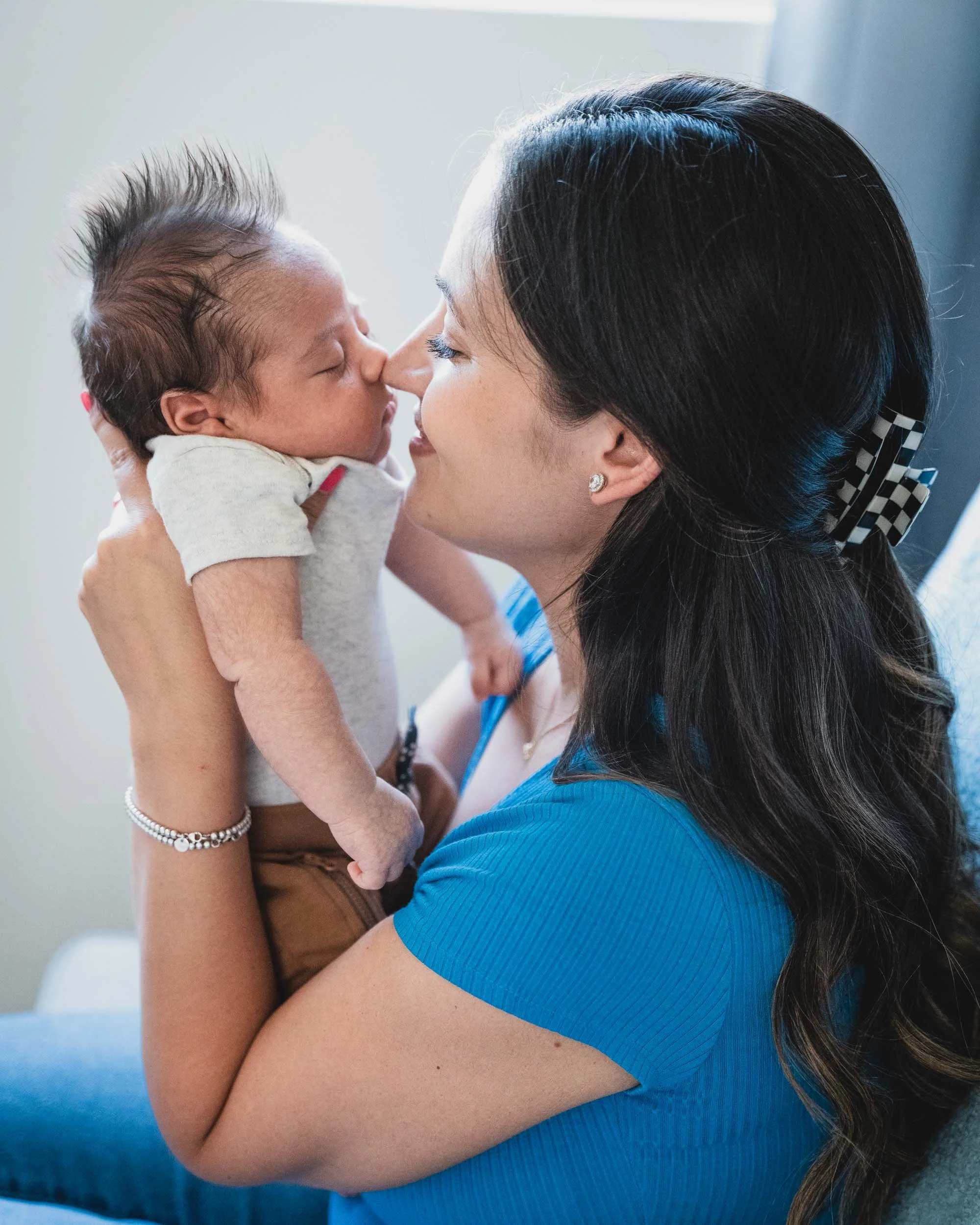 A mom is touching noses with her sweet new baby boy. 
