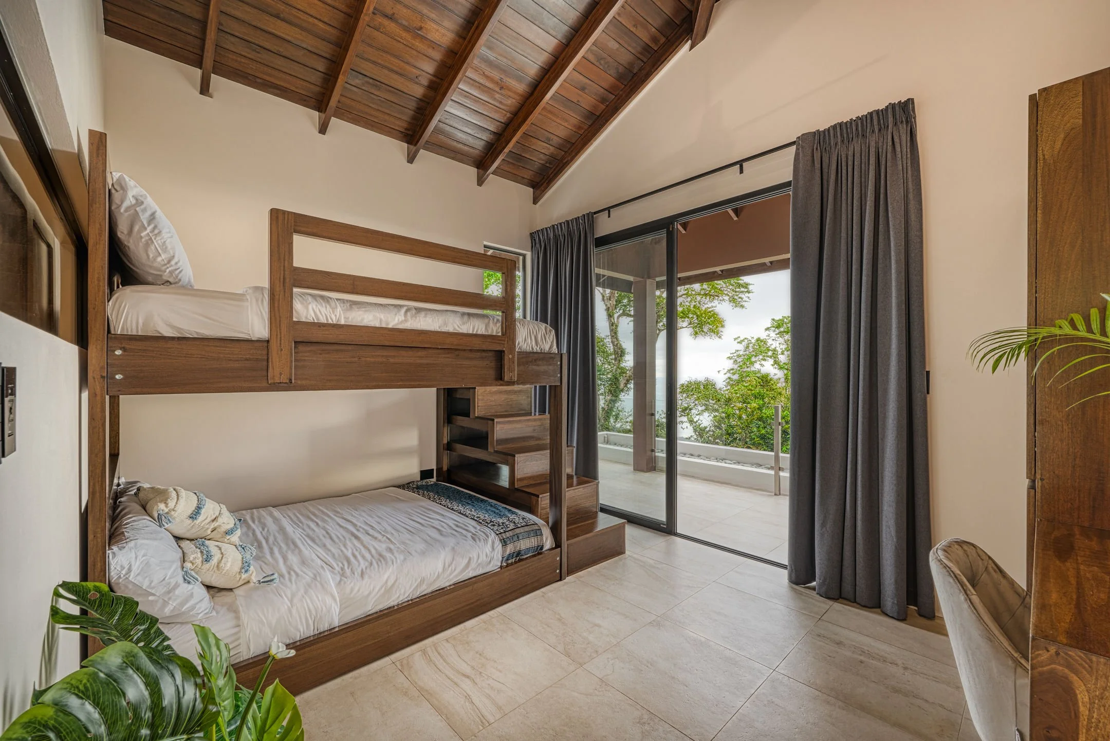 Bedroom with wooden bunk beds, sliding glass door leading to outdoor patio, and trees outside.
