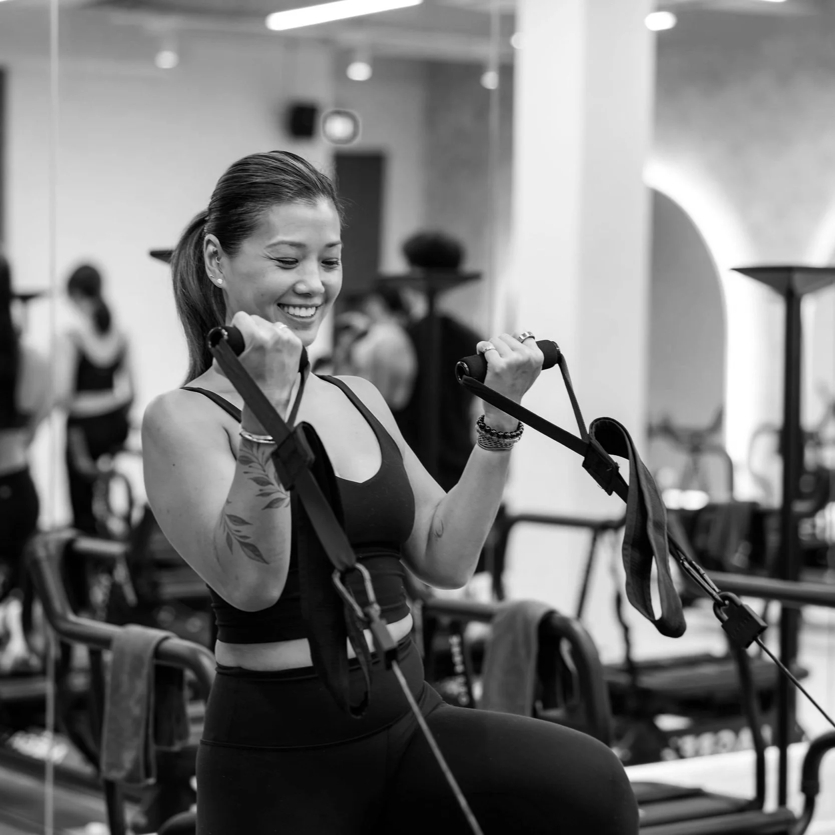 Woman exercising with resistance bands in gym, black and white photo.