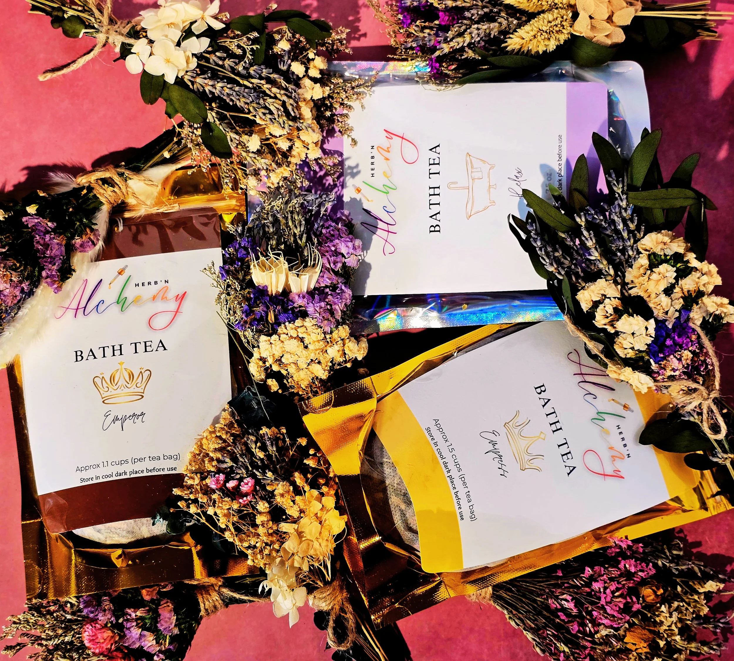 Gift sets of bath teas wrapped with dried flower arrangements and decorated with the Mother's Day theme, placed on a pink surface.