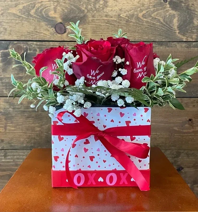 red roses and greenery in a white hat box with red hearts