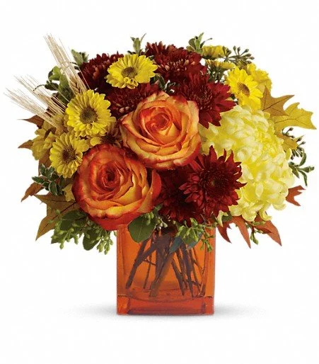 Fall colored fresh flowers in an orange glass cube
