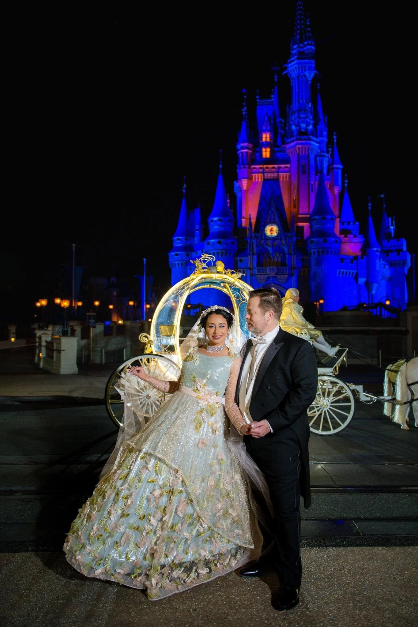 A bride and groom at Disney World with Cinderella's castle in the background, night scene with illuminated architecture.