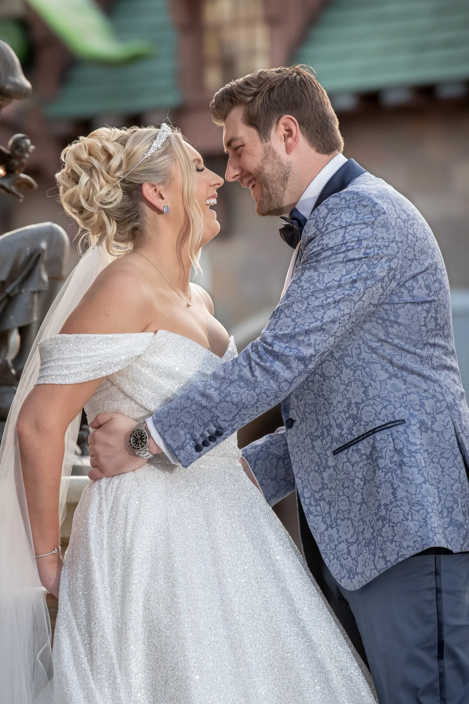 A bride and groom are smiling and face-to-face during their wedding ceremony, holding each other's arms.