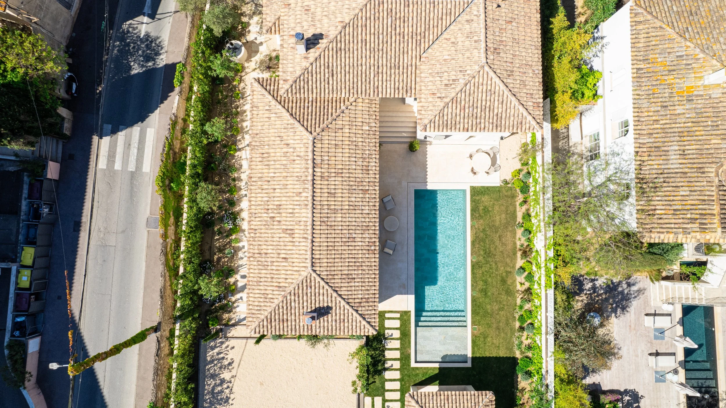 Vue aérienne d'une maison avec un jardin, une piscine et une terrasse, entourée de murs et de végétation.