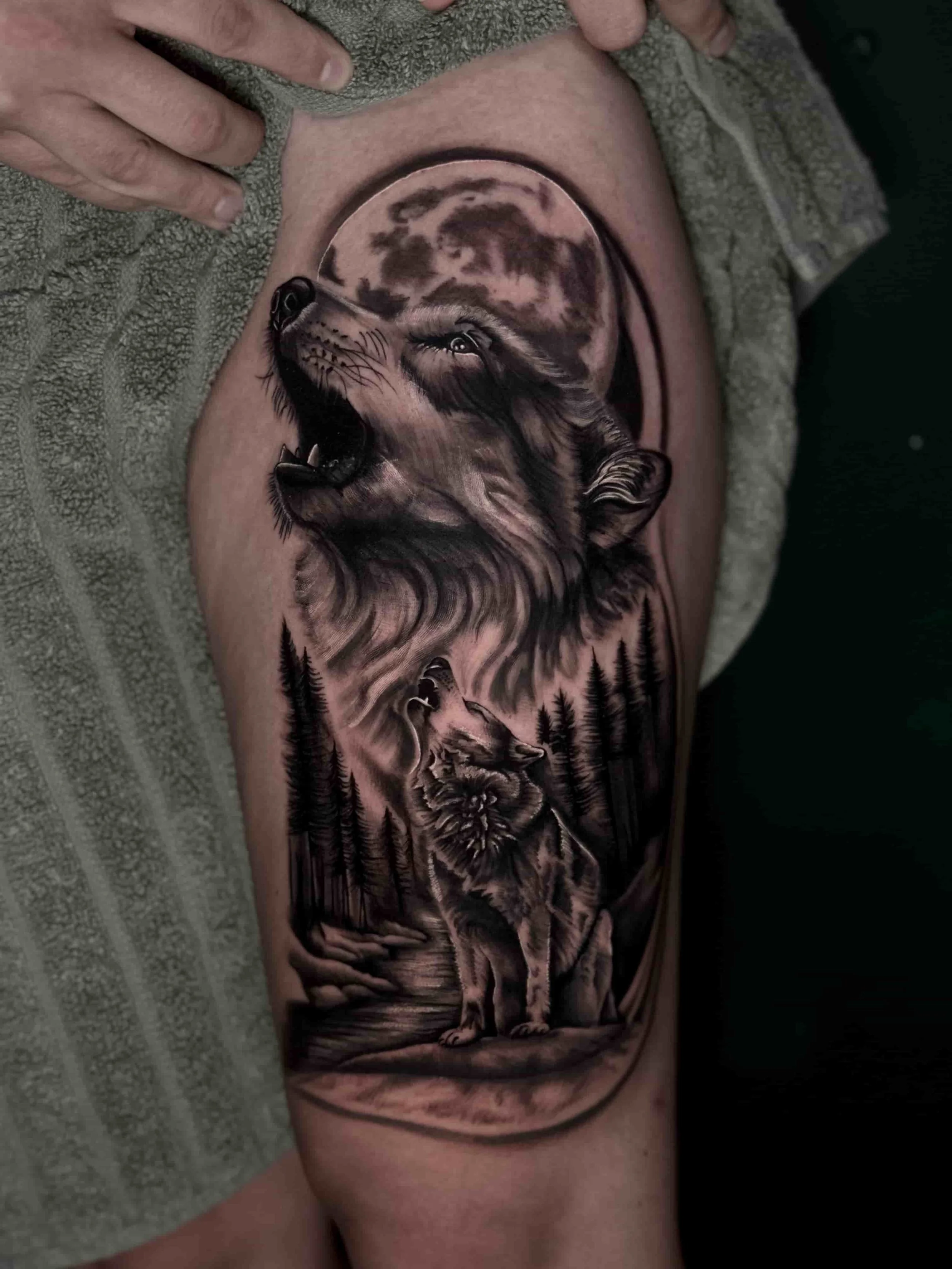 Two howling wolves with a moon in the background tattoo