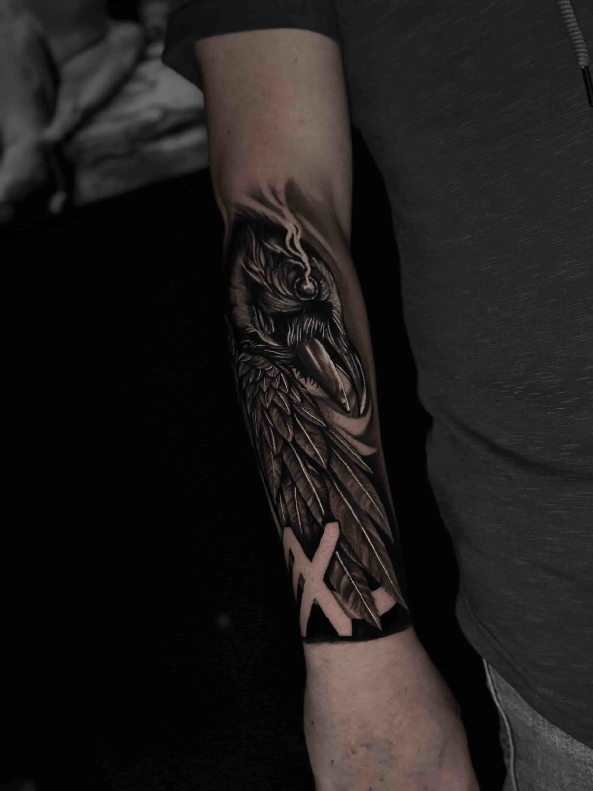 Black and grey realism crow bird tattoo on the forearm