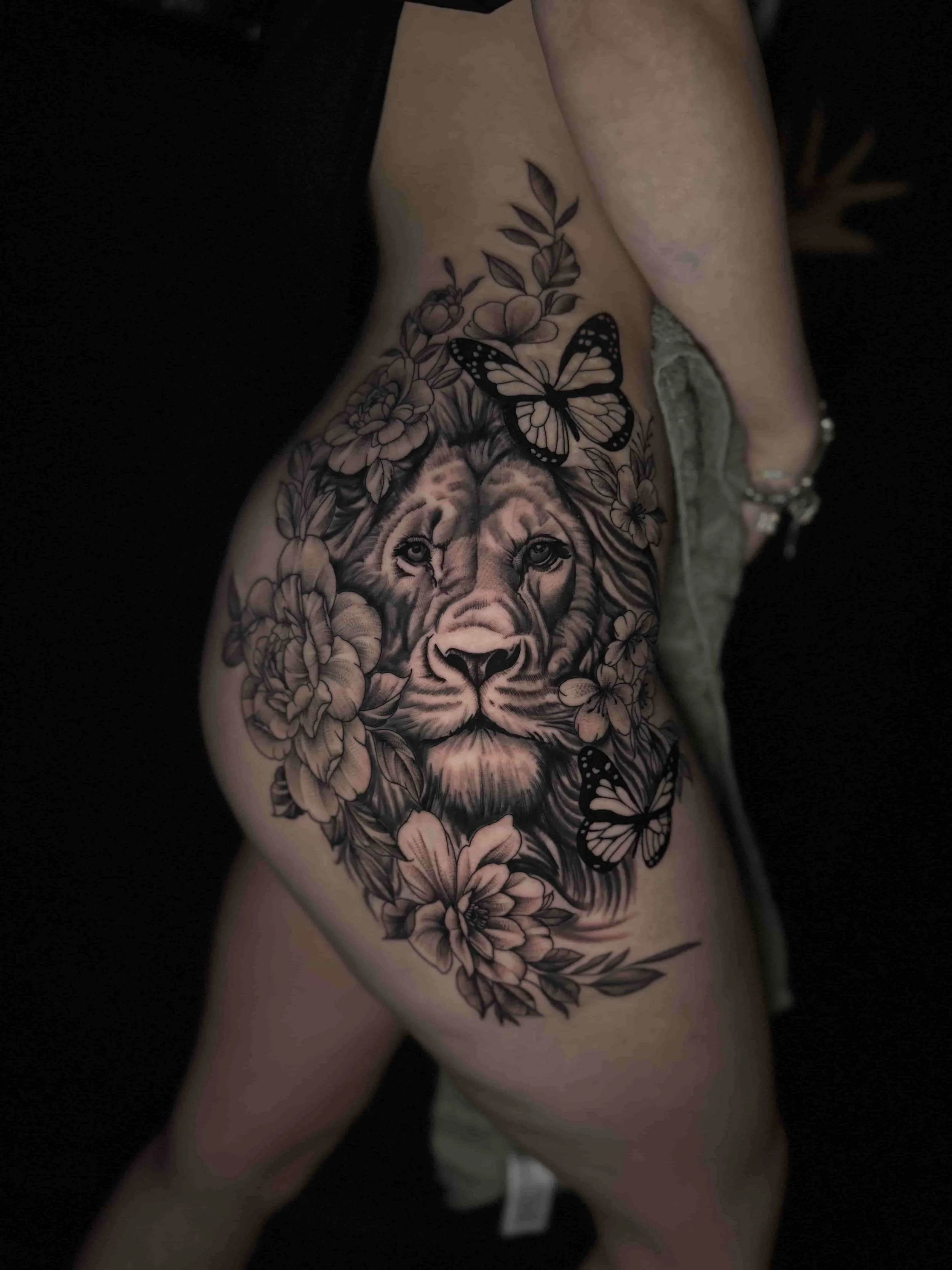 A realism lion with flowers on the thigh tattoo