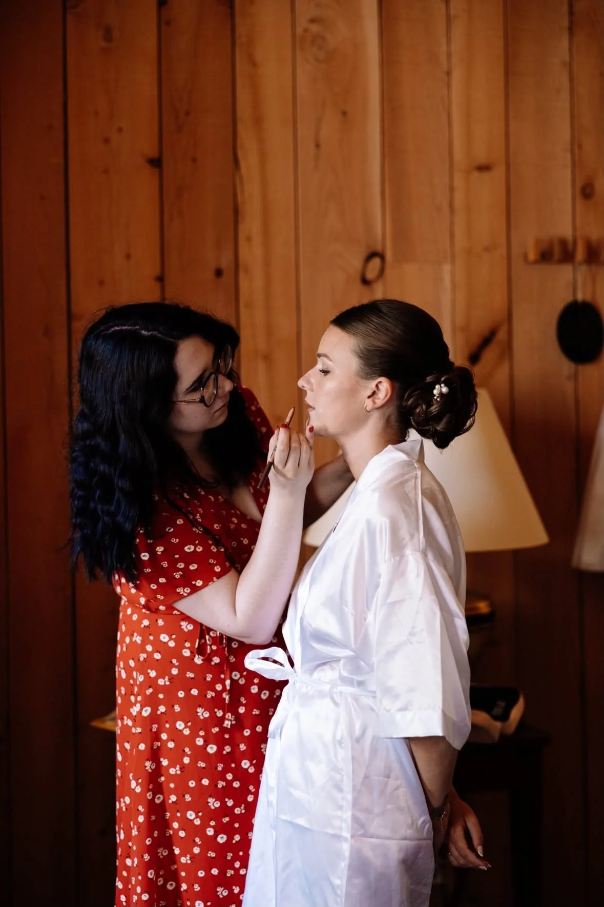 Armony, mariée en peignoir blanc : application du rouge à lèvres lors de son maquillage de mariée