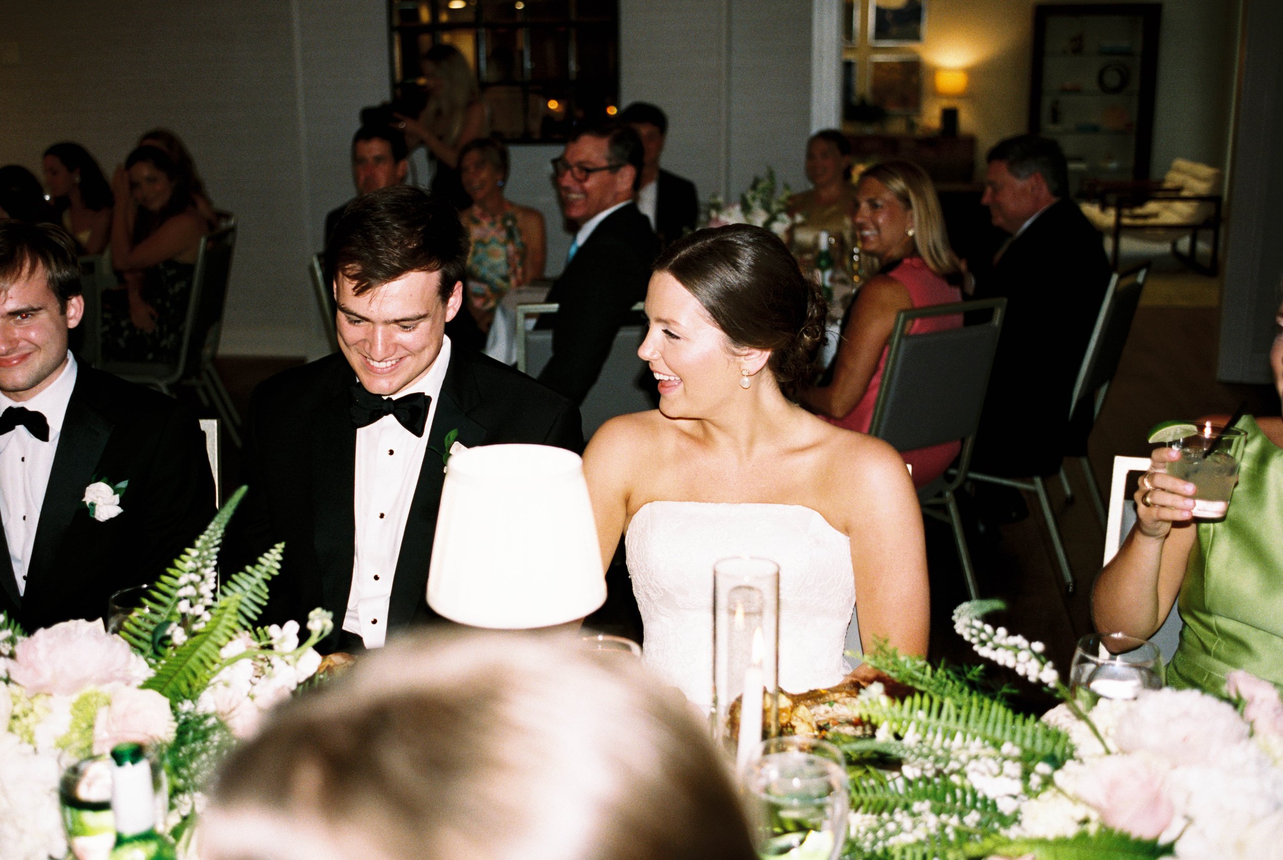A bride is hugging her mother and they are both smiling and emotional inside a home with elegant decor.