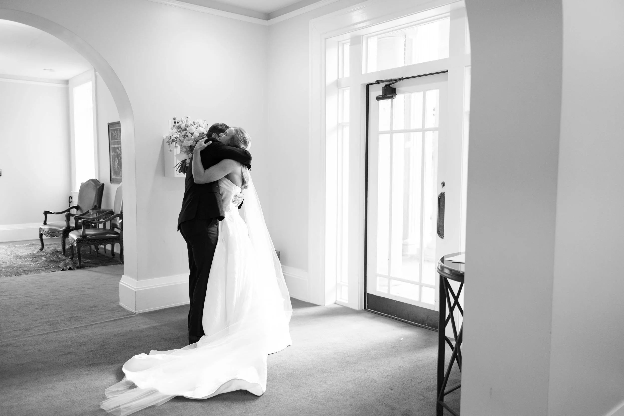 Bride and groom sharing a kiss at their wedding reception surrounded by guests.