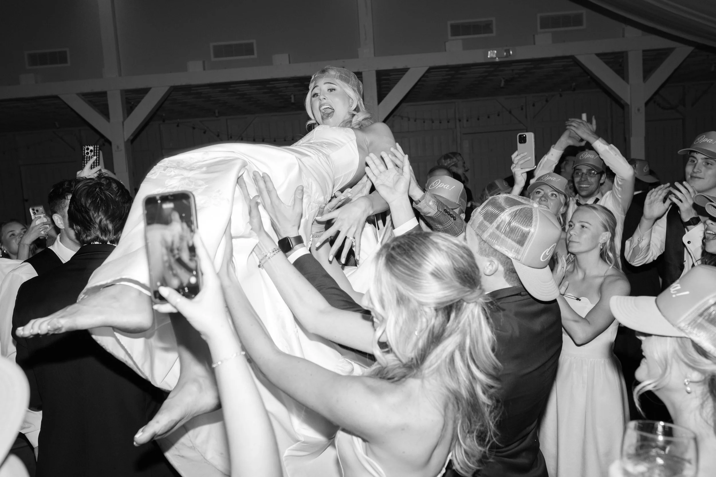 A woman in a green satin strapless dress appears to pour a drink on a man dancing on the floor at a party. The man, wearing a suit and a backward baseball cap, is on the ground with a happy expression. Other people are dancing and socializing in the background.