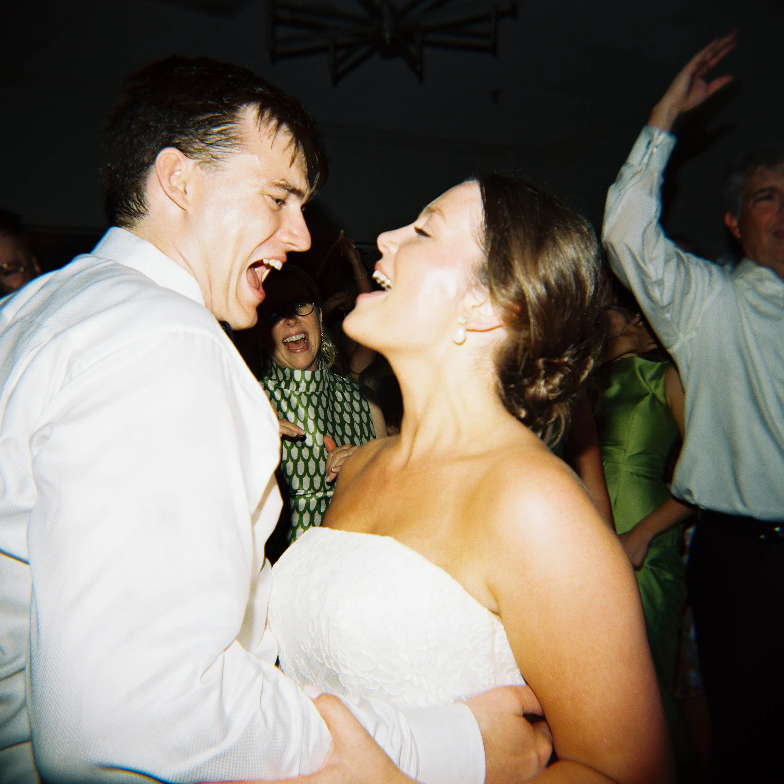 Two people, a man and a woman, are closely facing each other, smiling and singing along or enjoying music together in a lively setting, possibly a party or celebration.